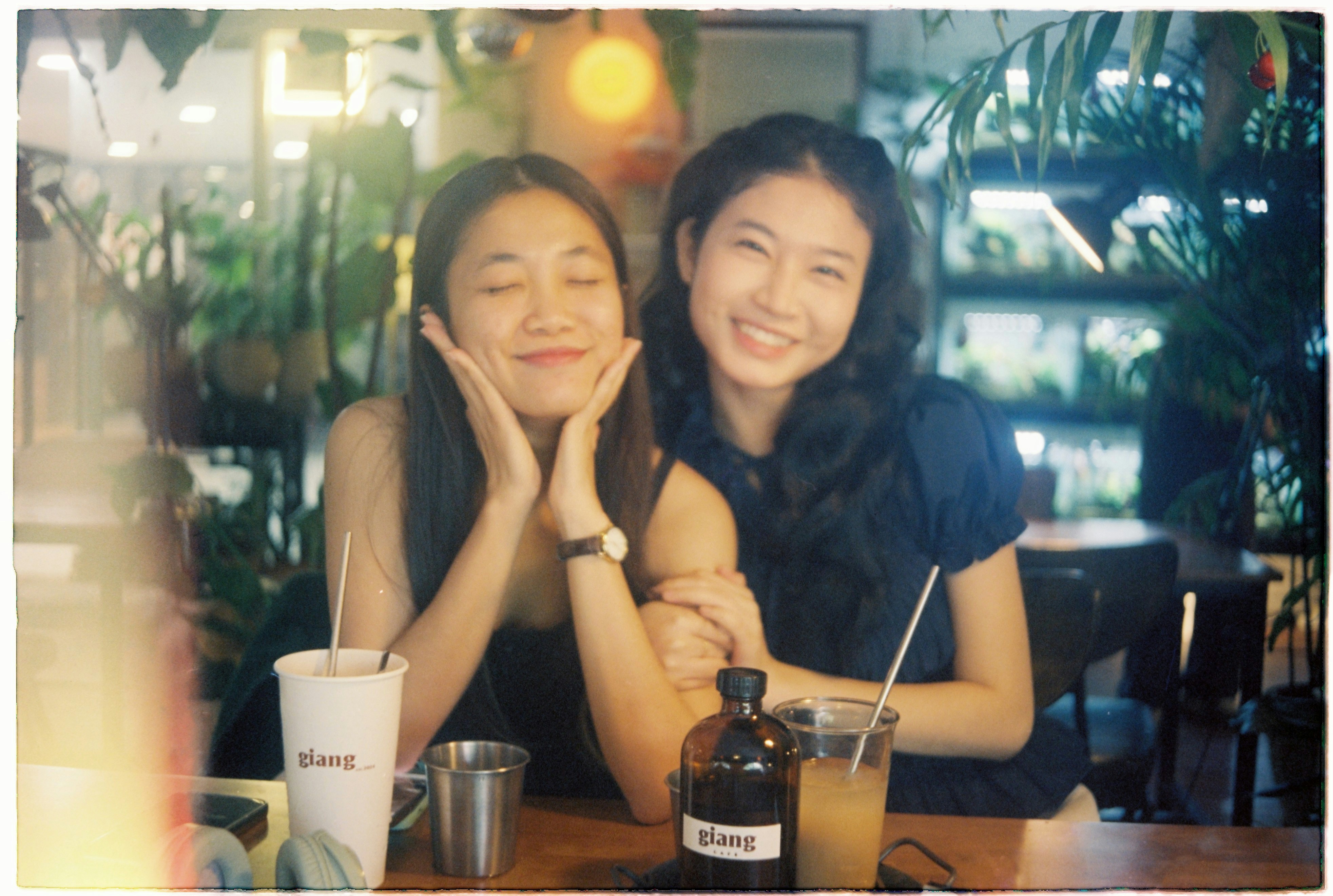 Two smiling young women at a table with drinks.