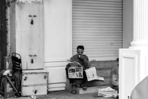 Man reading newspaper while sitting on steps.