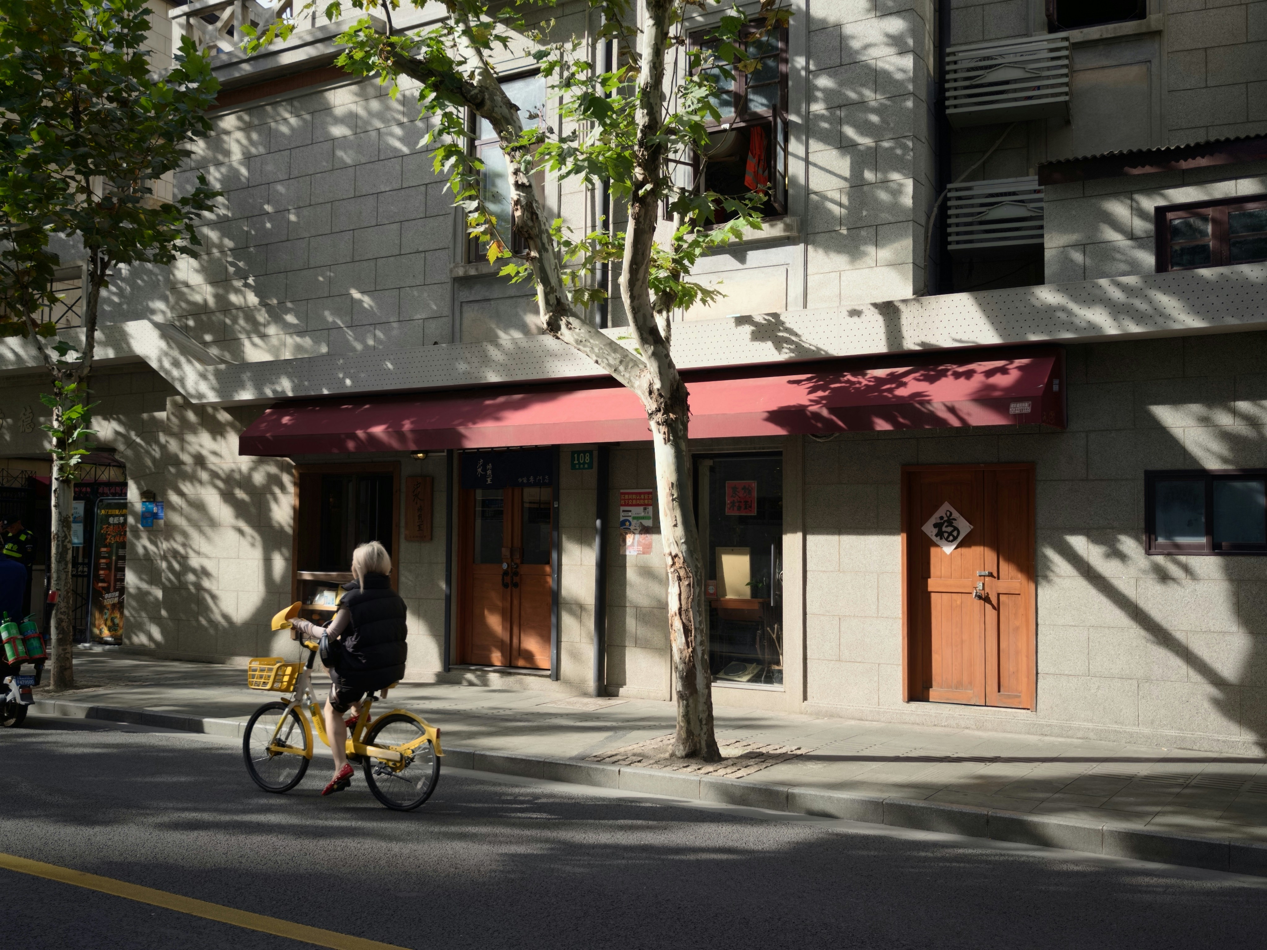 Une femme chevauche un vélo jaune dans une rue ensoleillée.