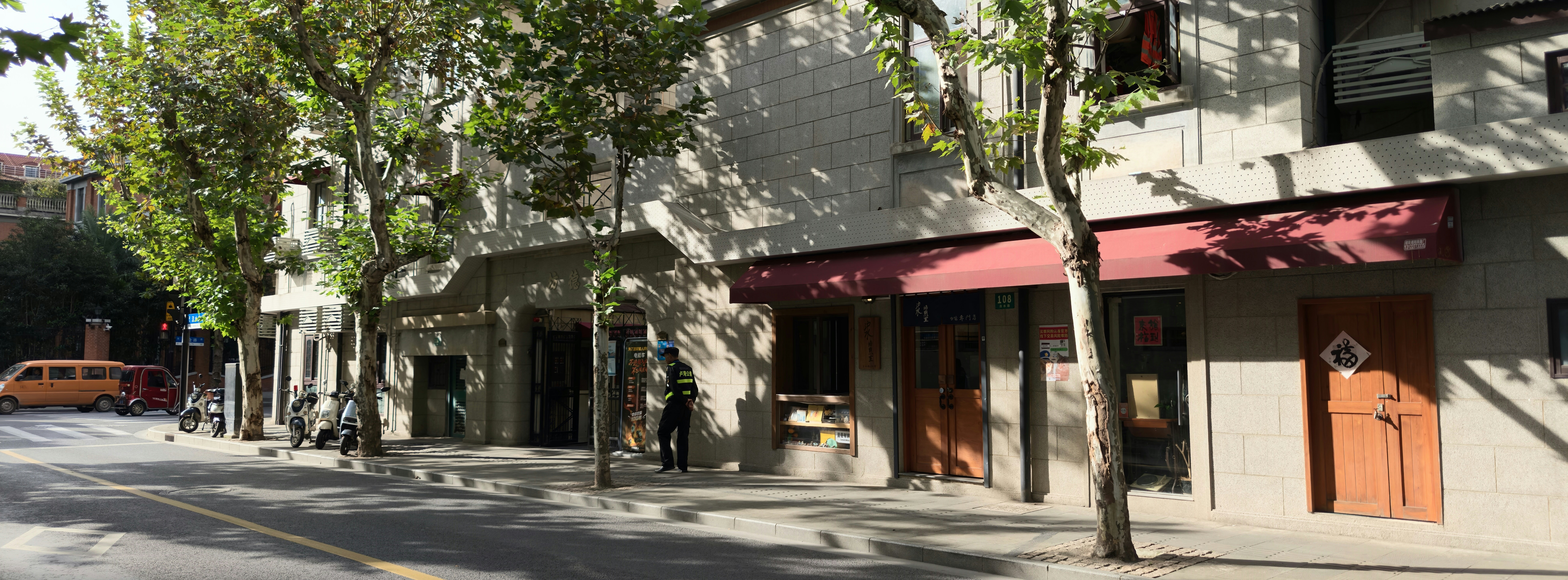 Vue de rue de bâtiments avec des arbres et des auvents.
