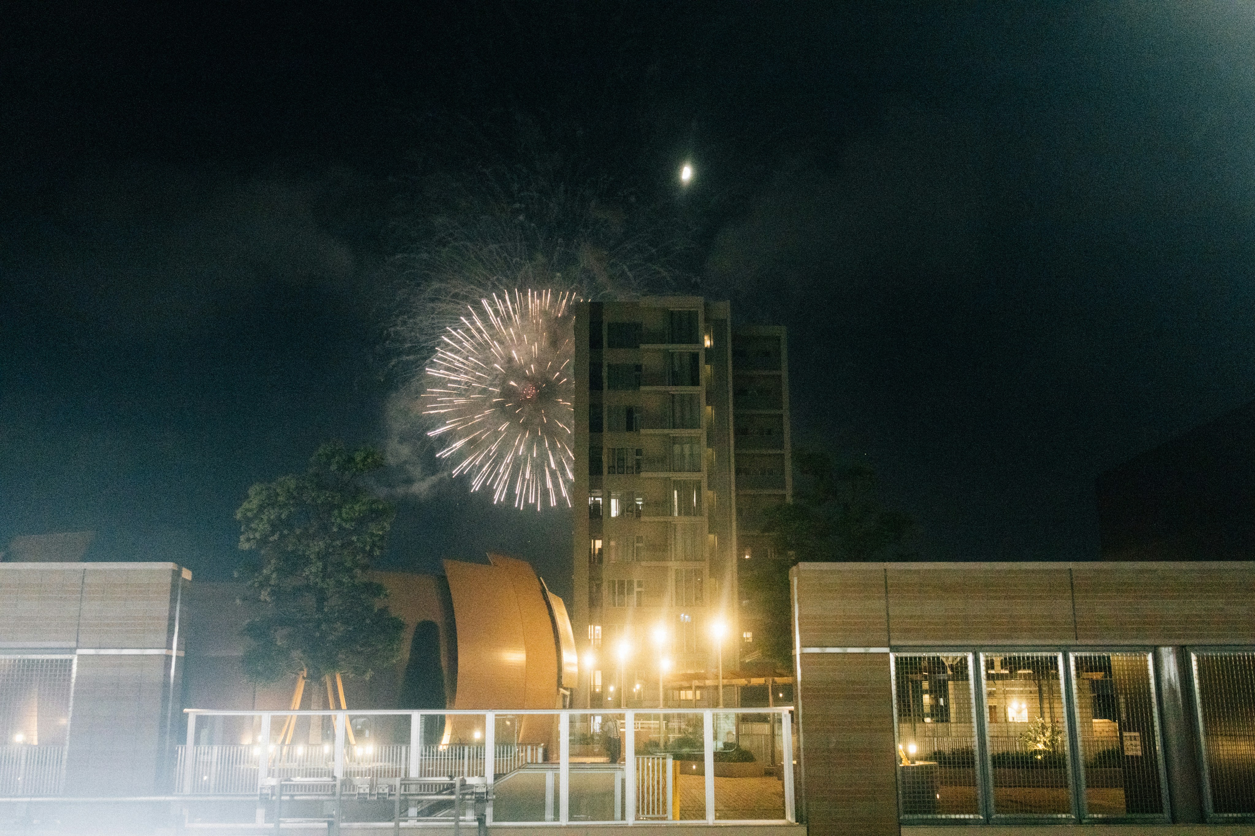 Fireworks explode over a building at night.