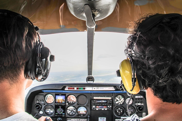 Two people in airplane cockpit flying over clouds