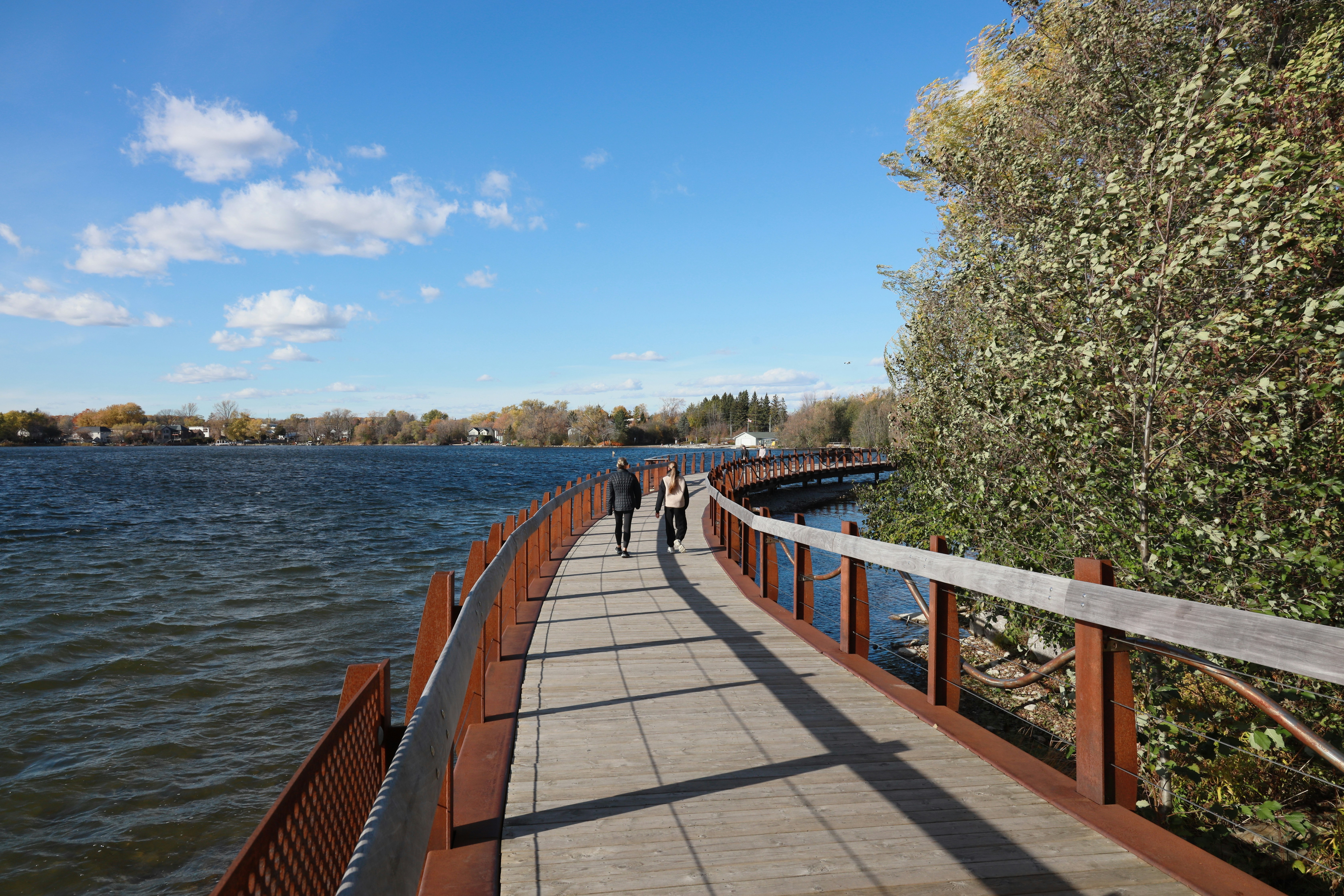 People walking on a boardwalk by a lake