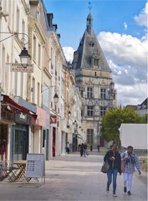 People walk down a street with historic buildings.