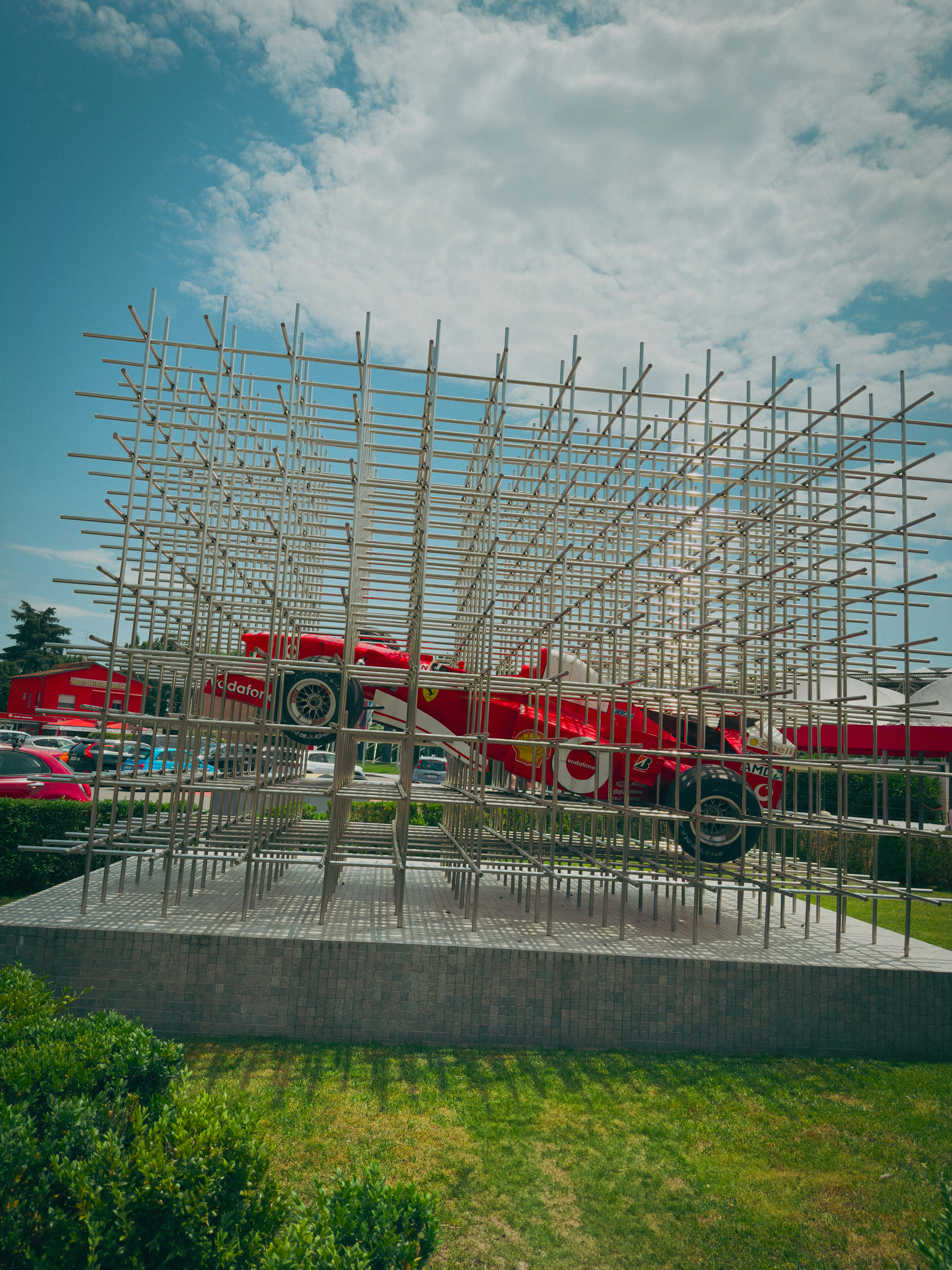Red race car sculpture framed by metal bars