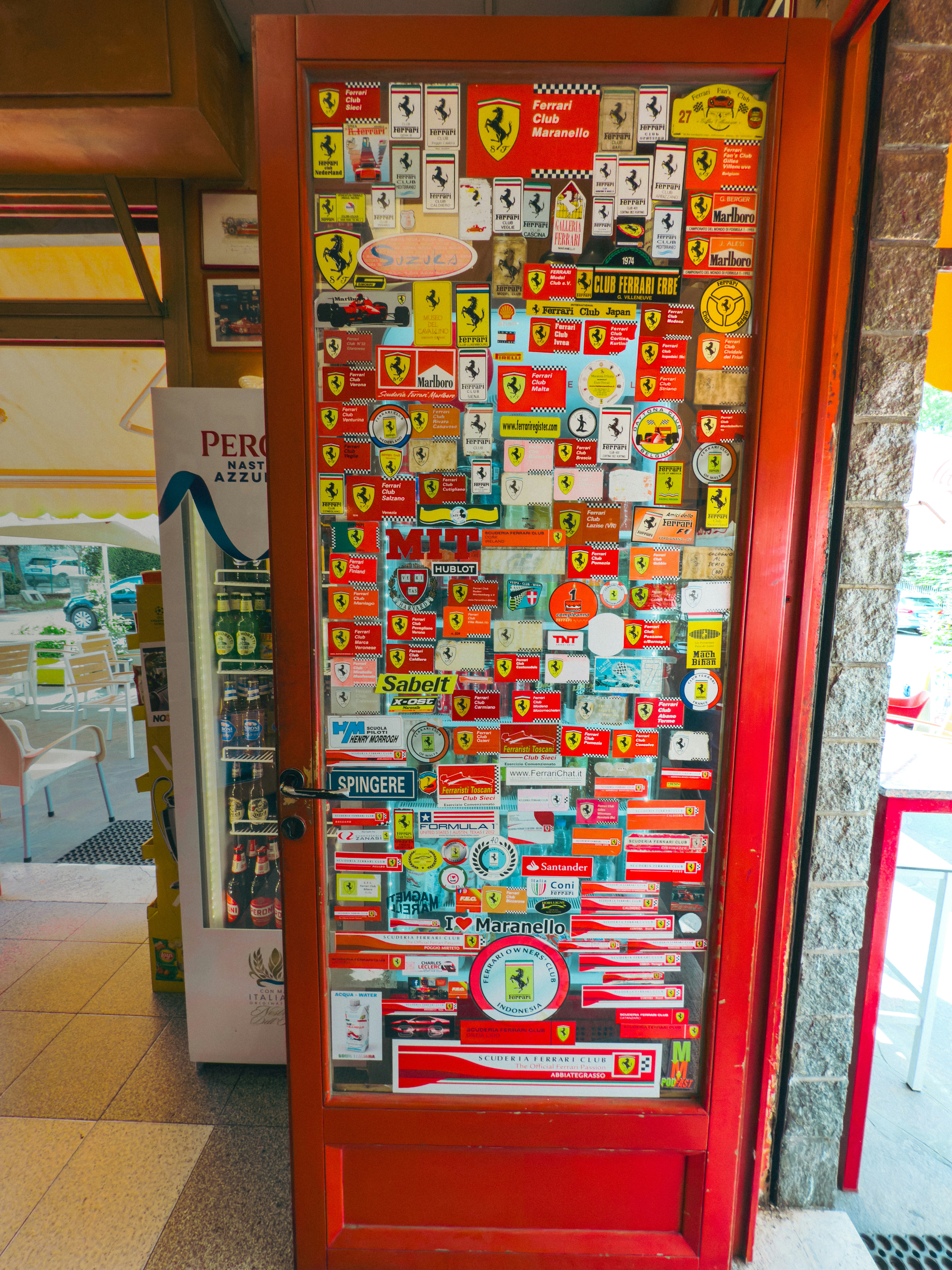 Red door covered in ferrari stickers and memorabilia