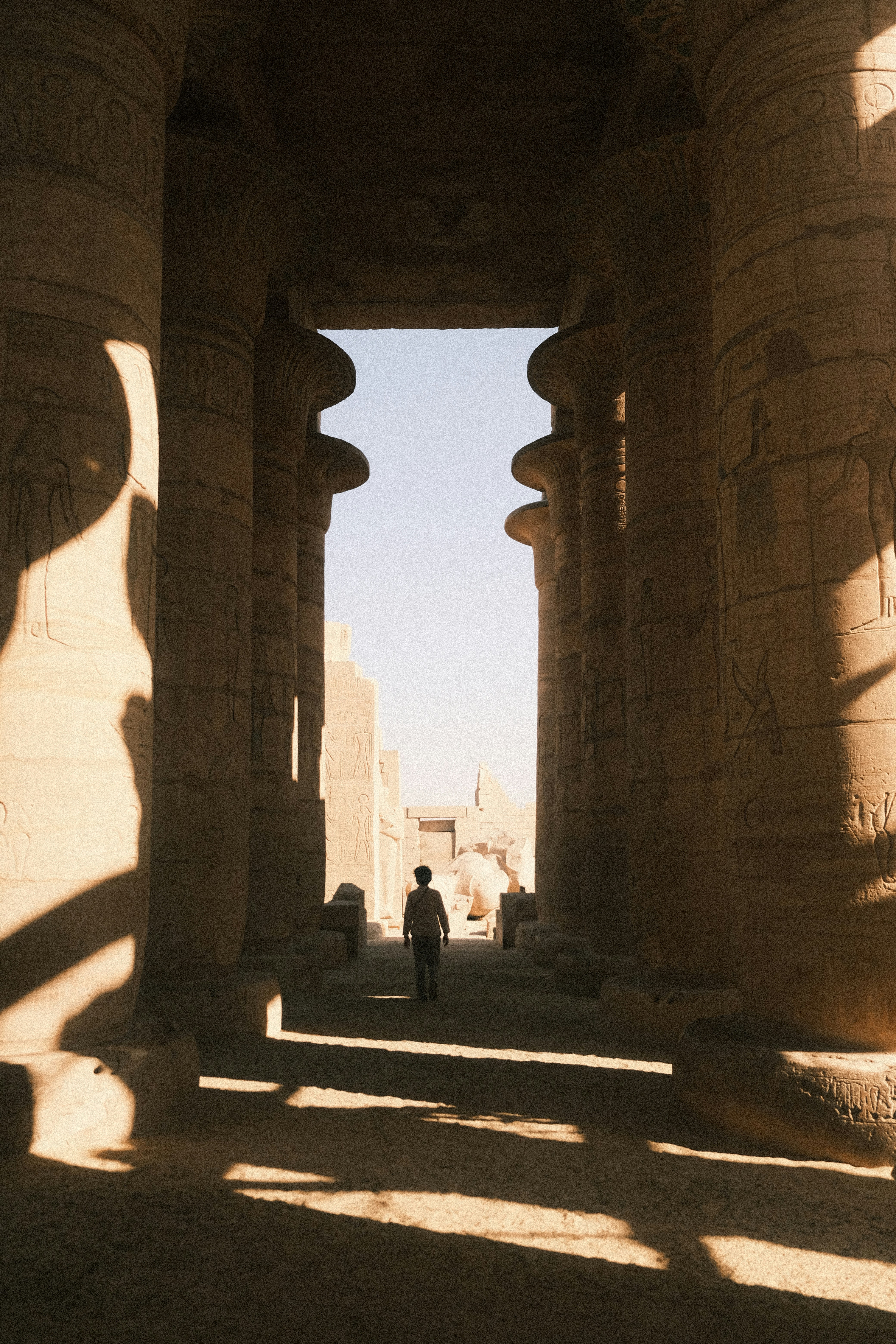 A person walks through a grand ancient egyptian temple hall.