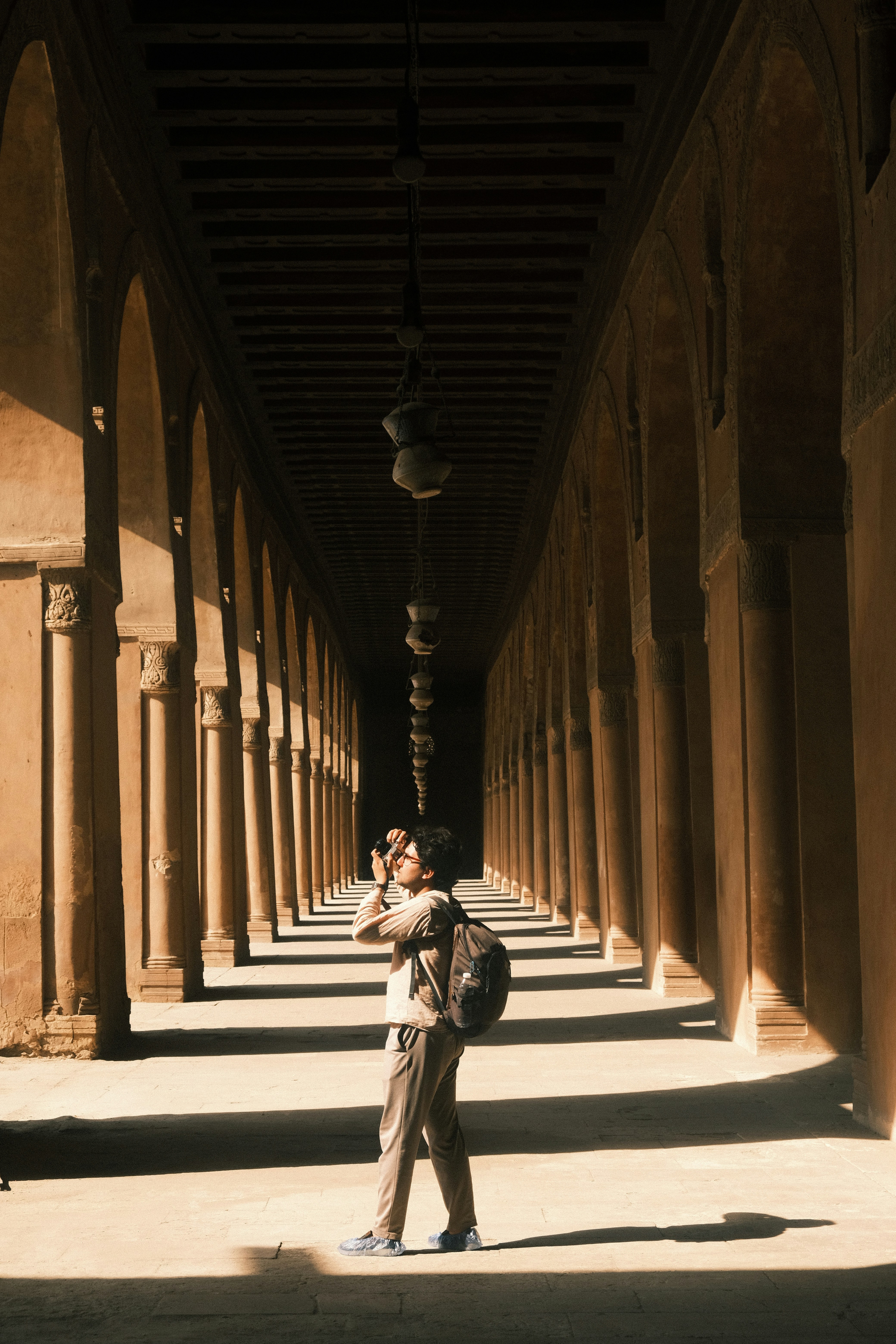 Man photographing ancient arched corridor with sunlight