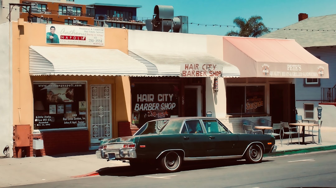 Dark green car parked outside barber shop.