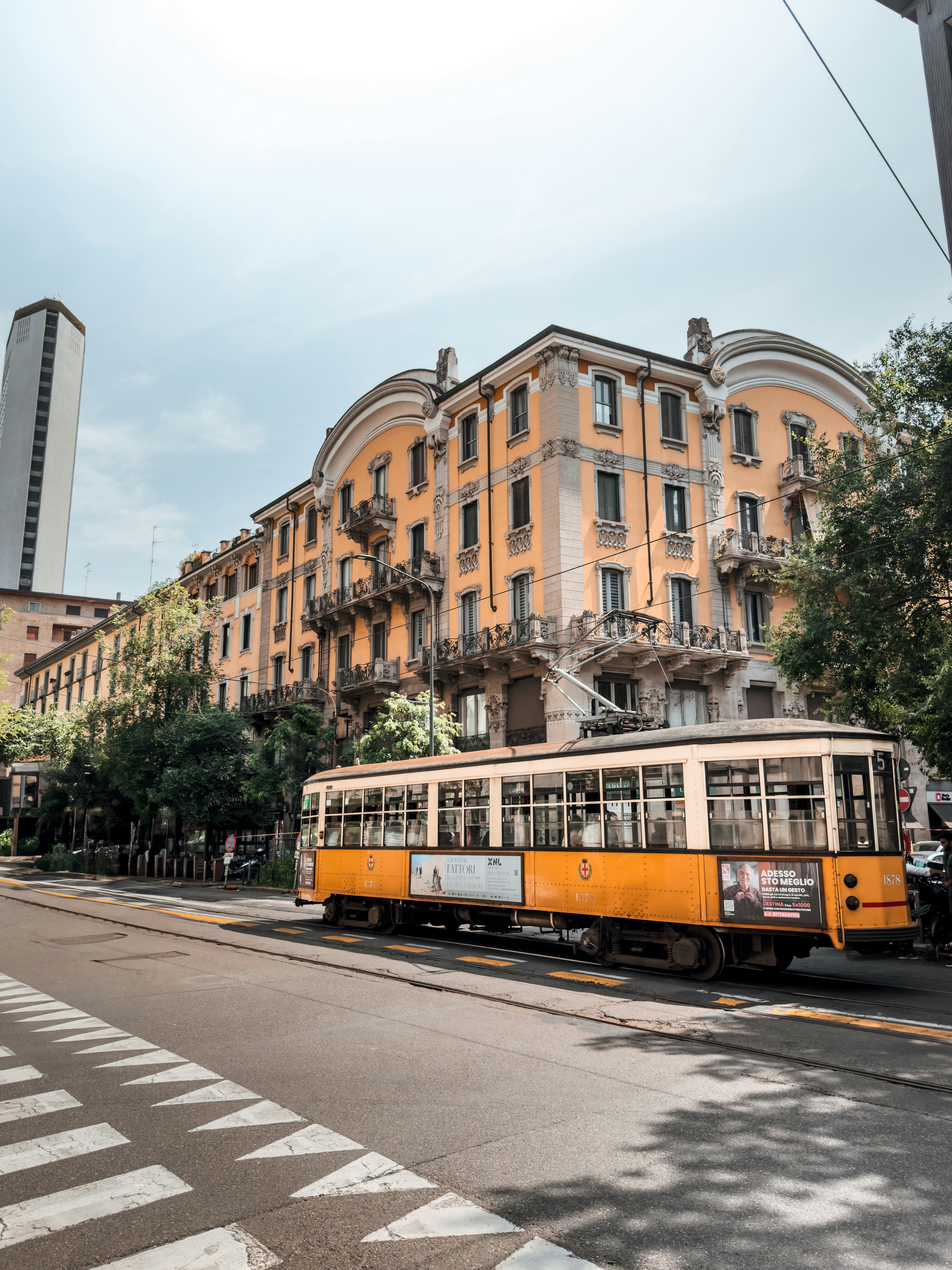 Yellow tram on a city street with buildings.