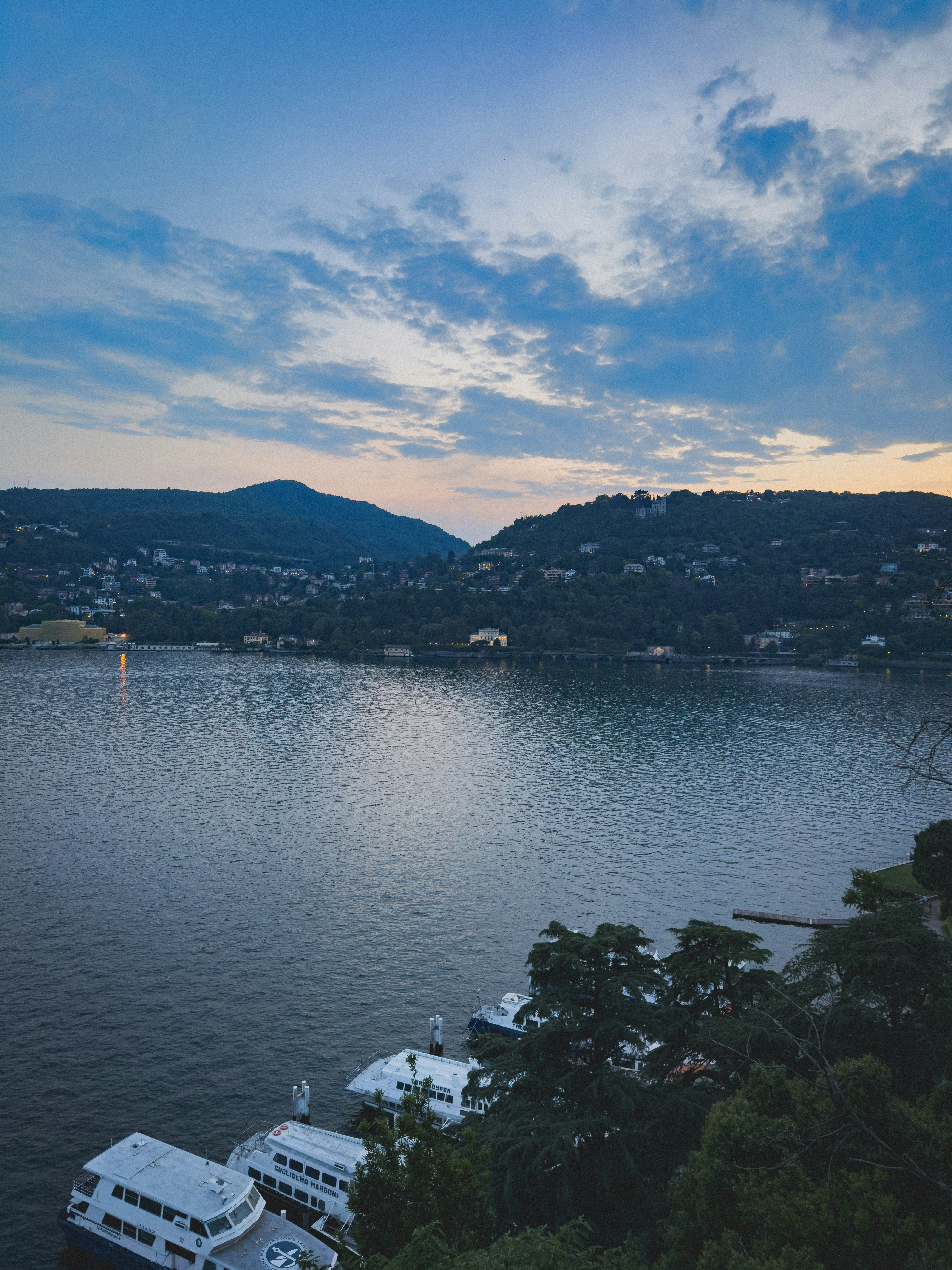 Boats docked on a serene lake at dusk.