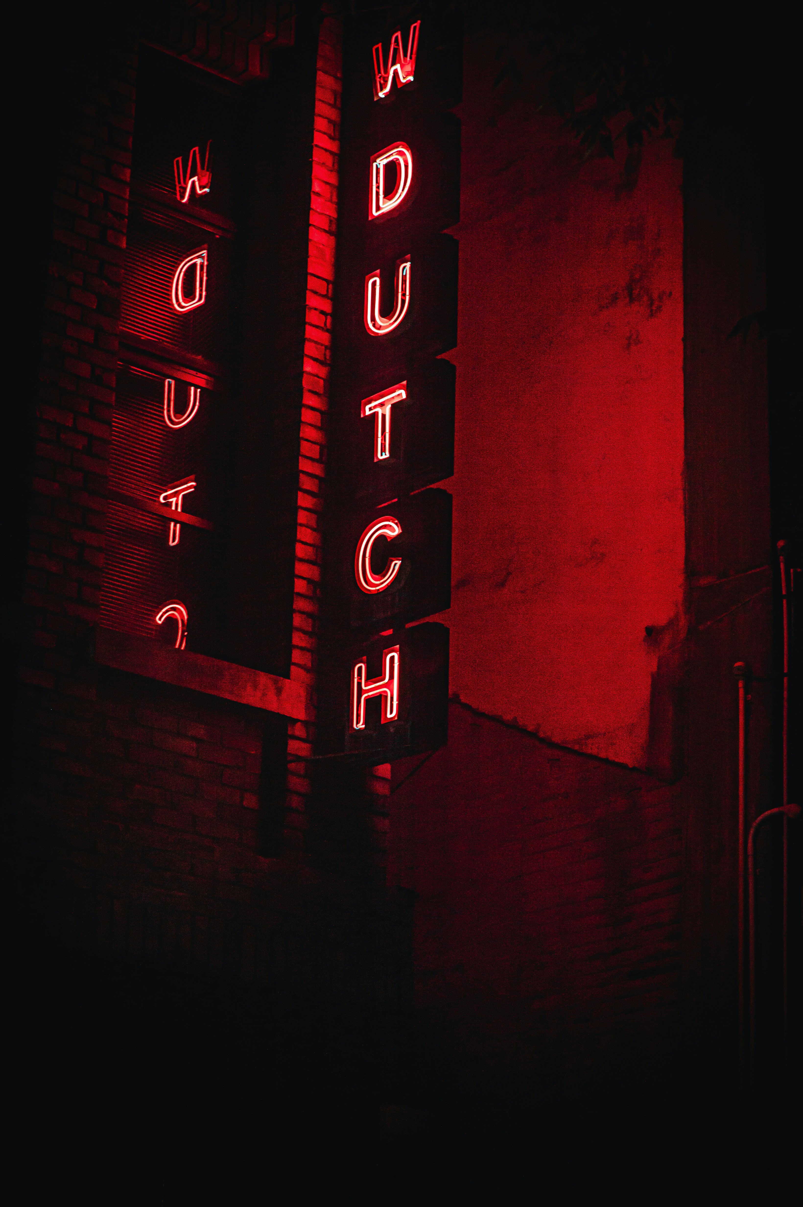Red neon sign spelling out "watch" at night.