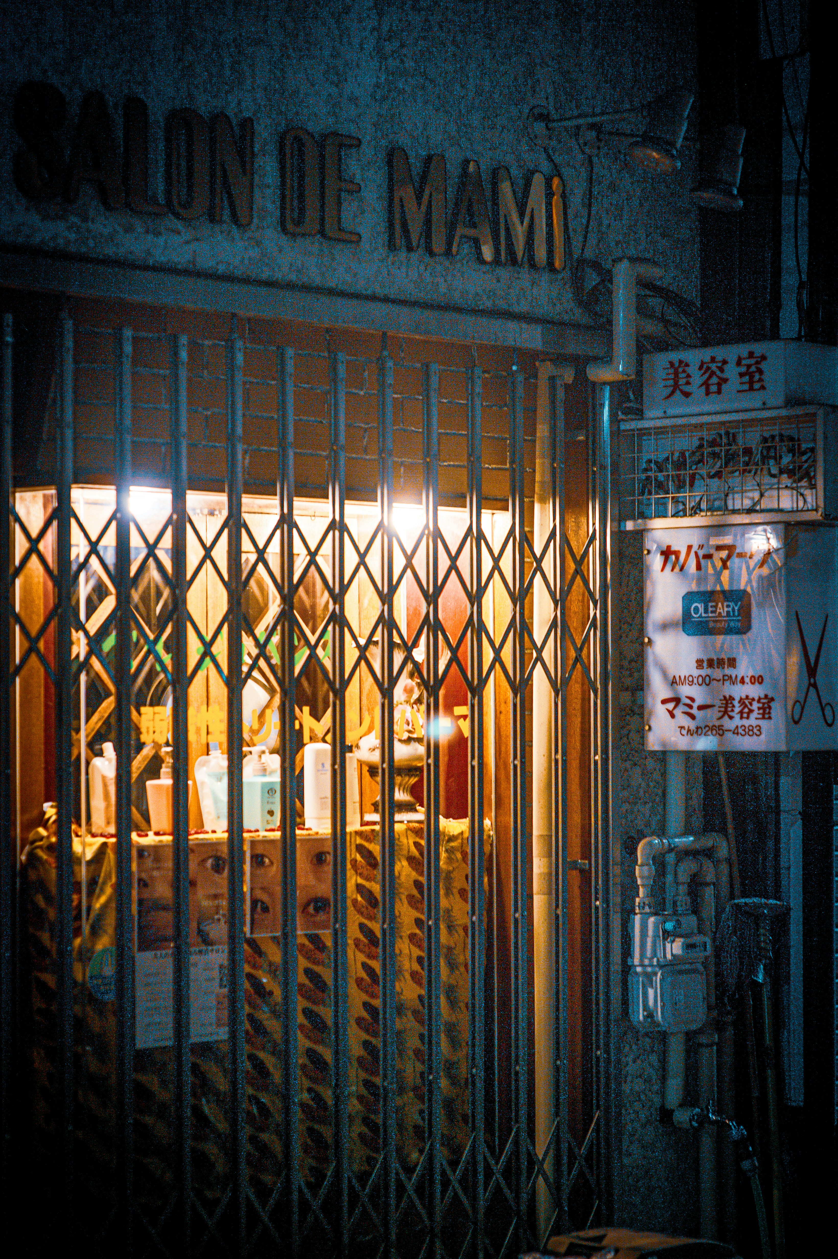 Salon de mami storefront at night with gate closed