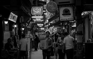 People walking down a busy, narrow street at night.