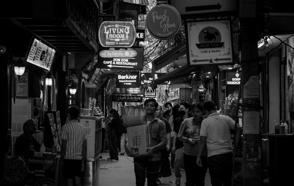 People walking down a busy, narrow street at night.