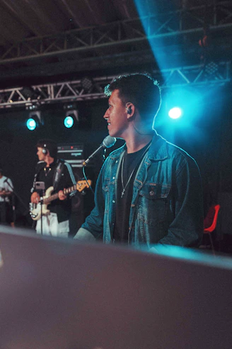 Man singing on stage with band performing behind