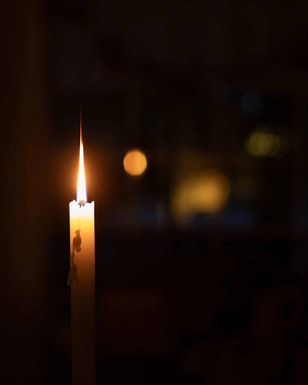 A single lit candle in the dark