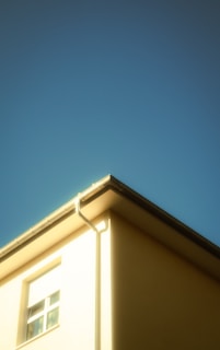 Corner of a building in Кричим with newly installed house guttering against a clear blue sky.