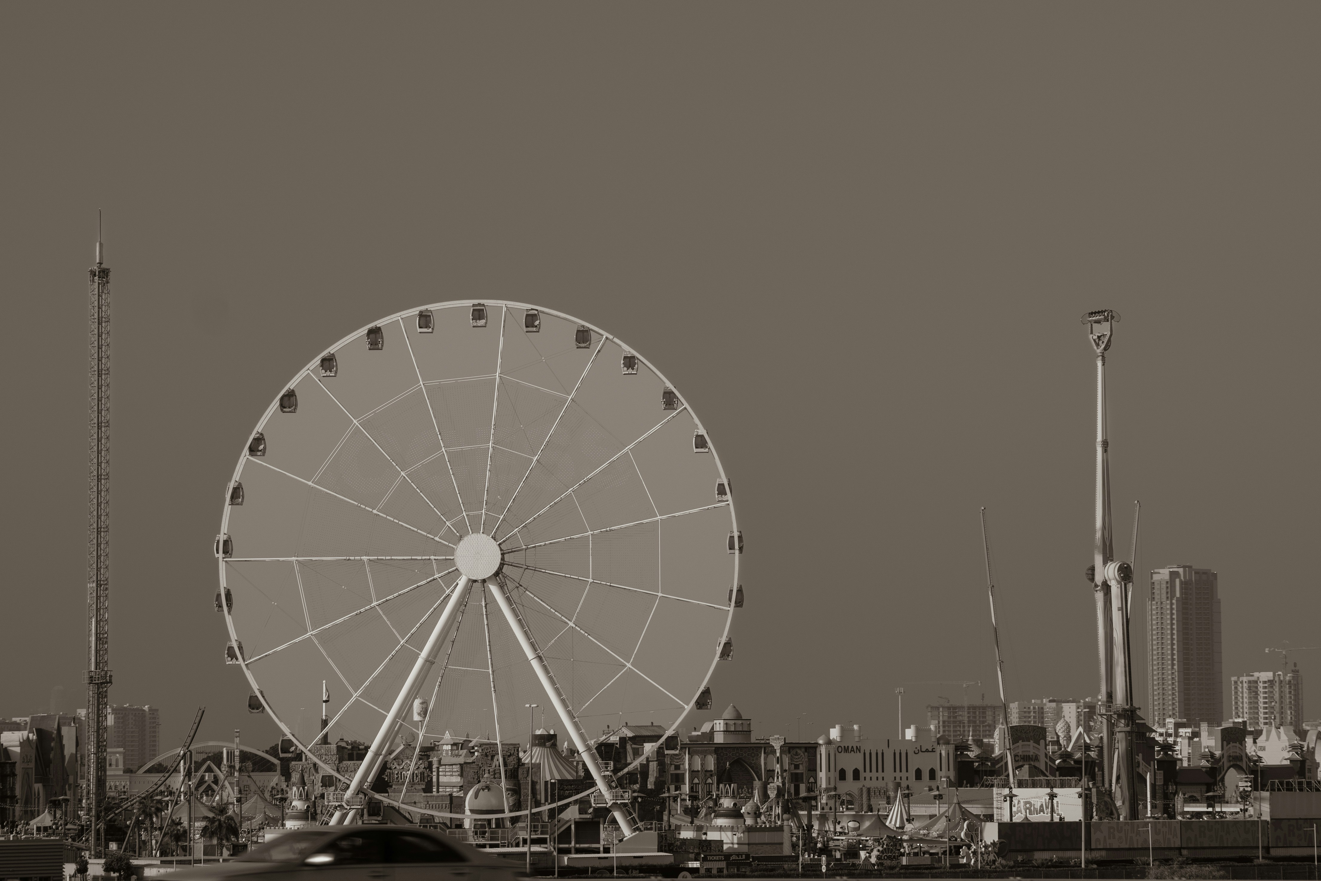 Ferris wheel against a clear sky with cityscape.