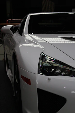White sports car with sleek headlights and spoiler.