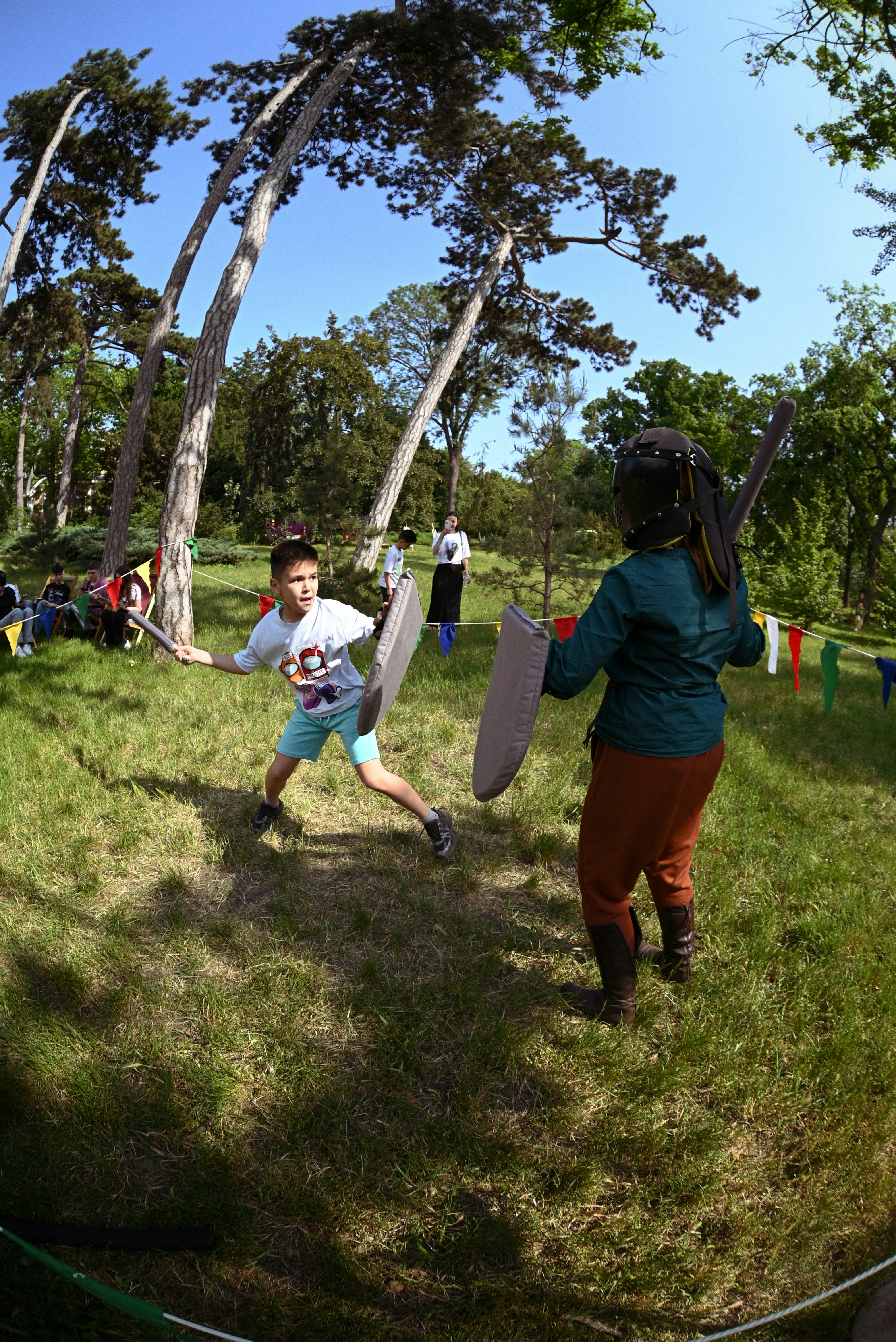 Boy and adult practicing sword fighting in a park.