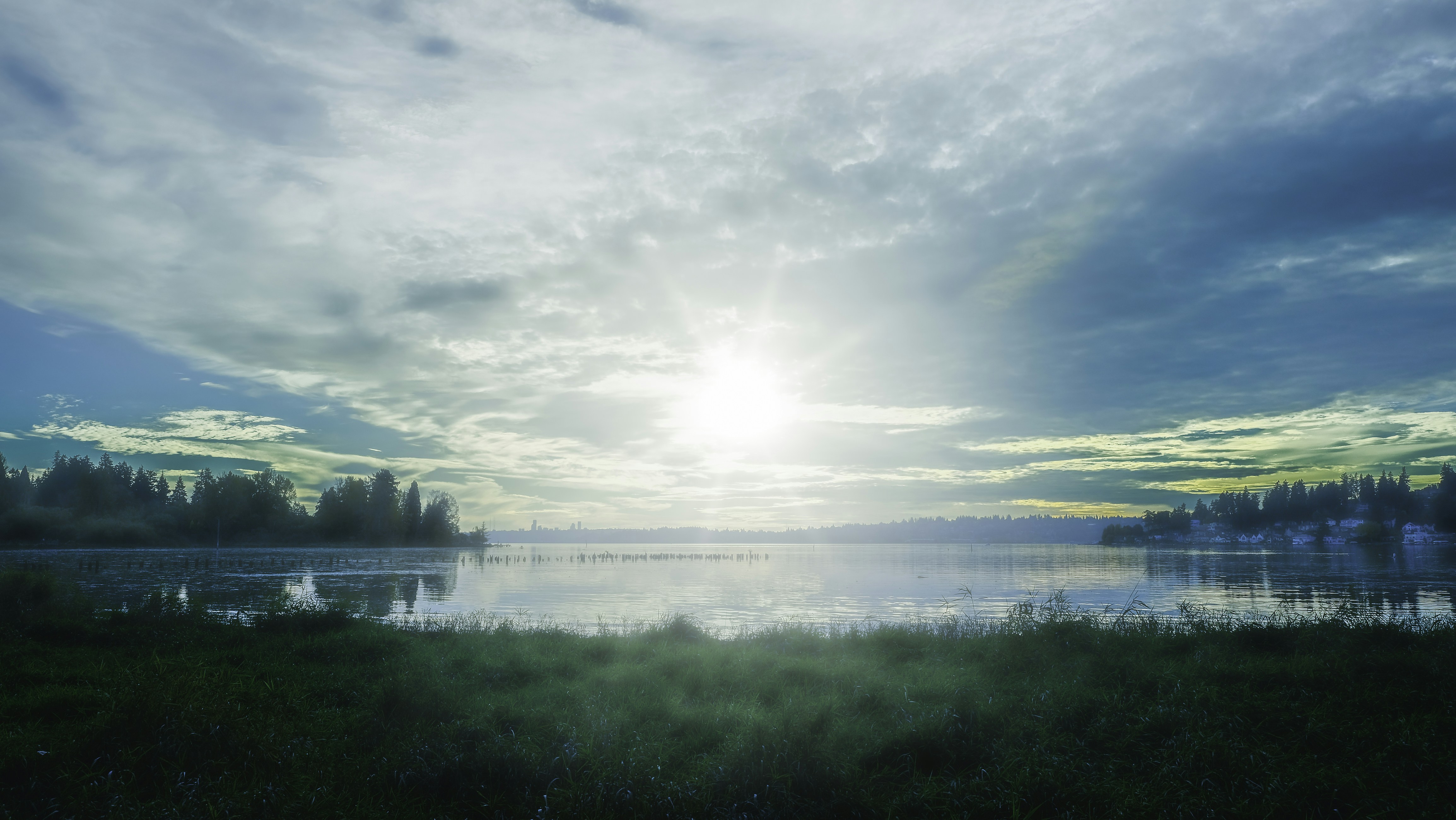 Sun shines over a calm lake with trees