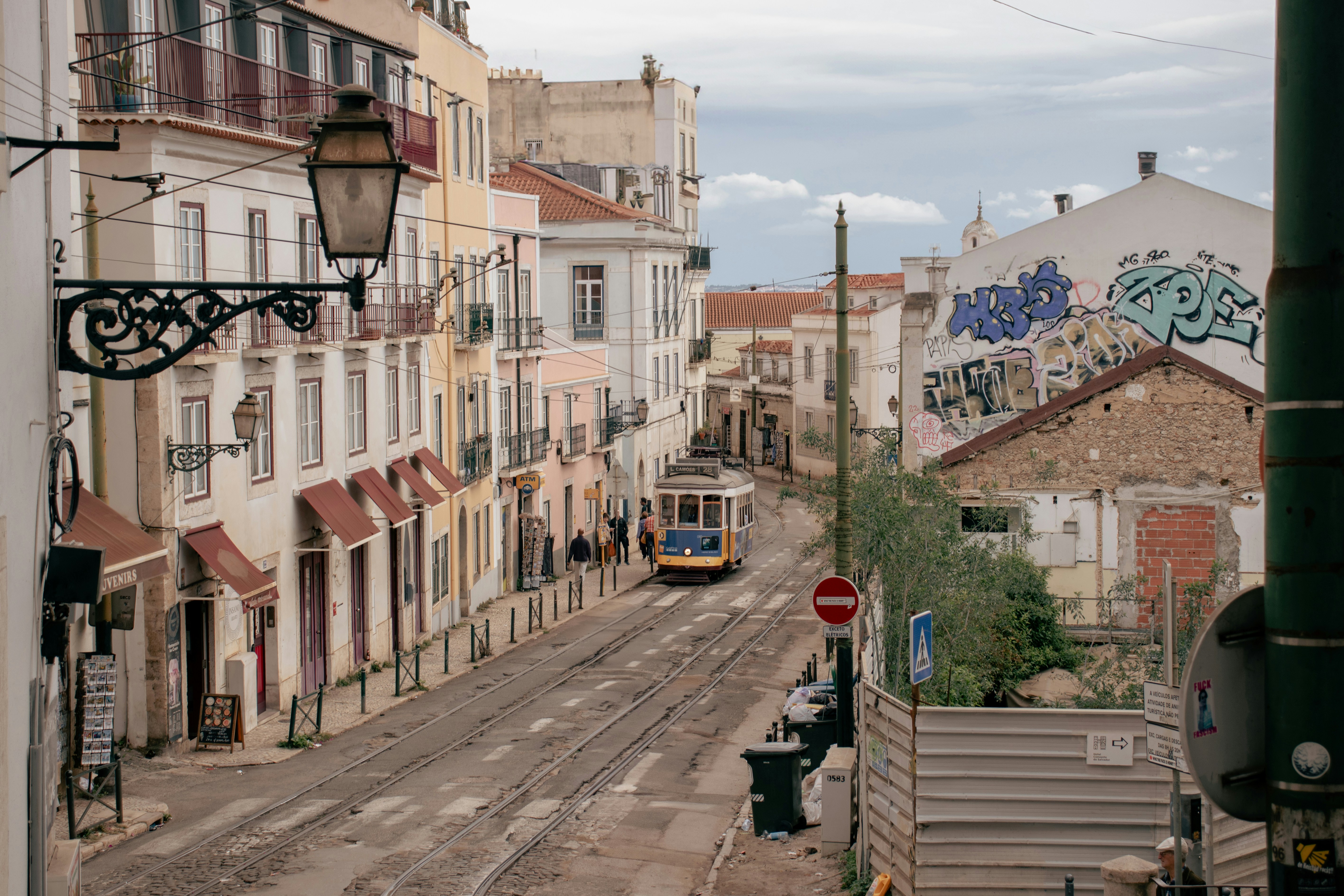 Yellow tram on a narrow Lisbon street lined with pastel buildings