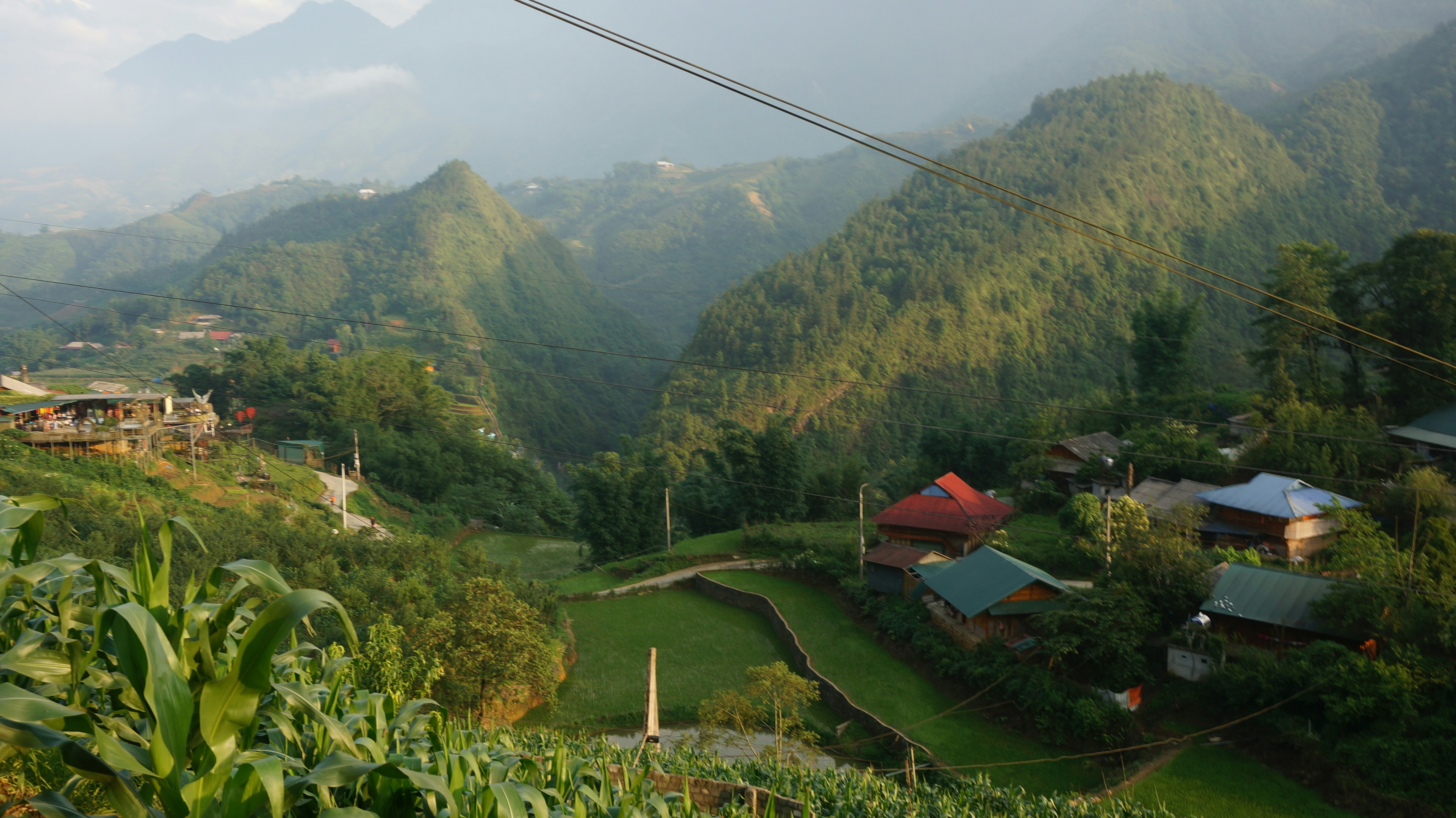 Green terraced hills with small village and mountains.