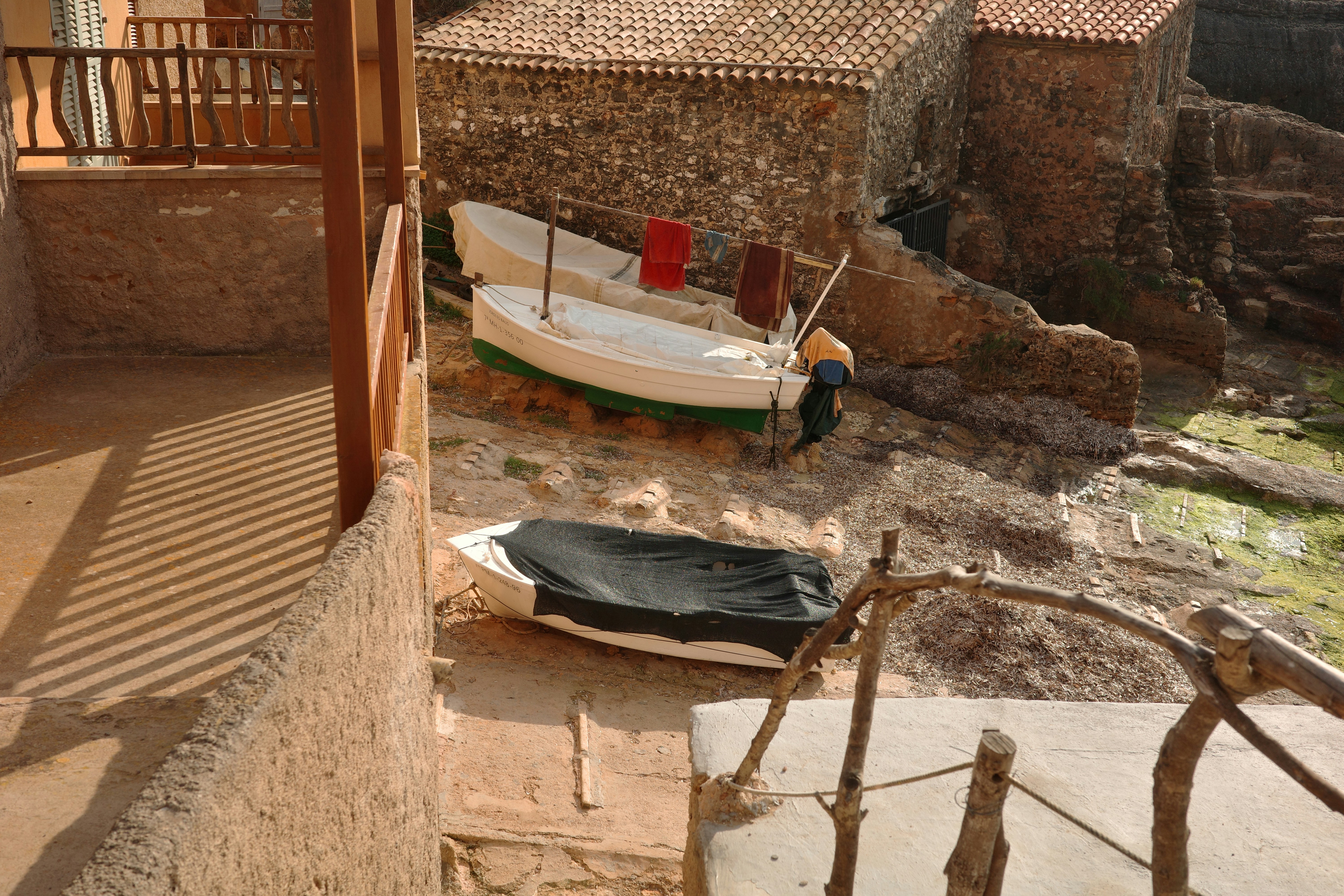 Two boats resting on a rocky shore near buildings.