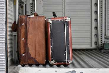 Two vintage suitcases on a ribbed surface.
