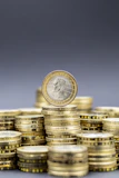 Stacks of gold coins with one coin on top