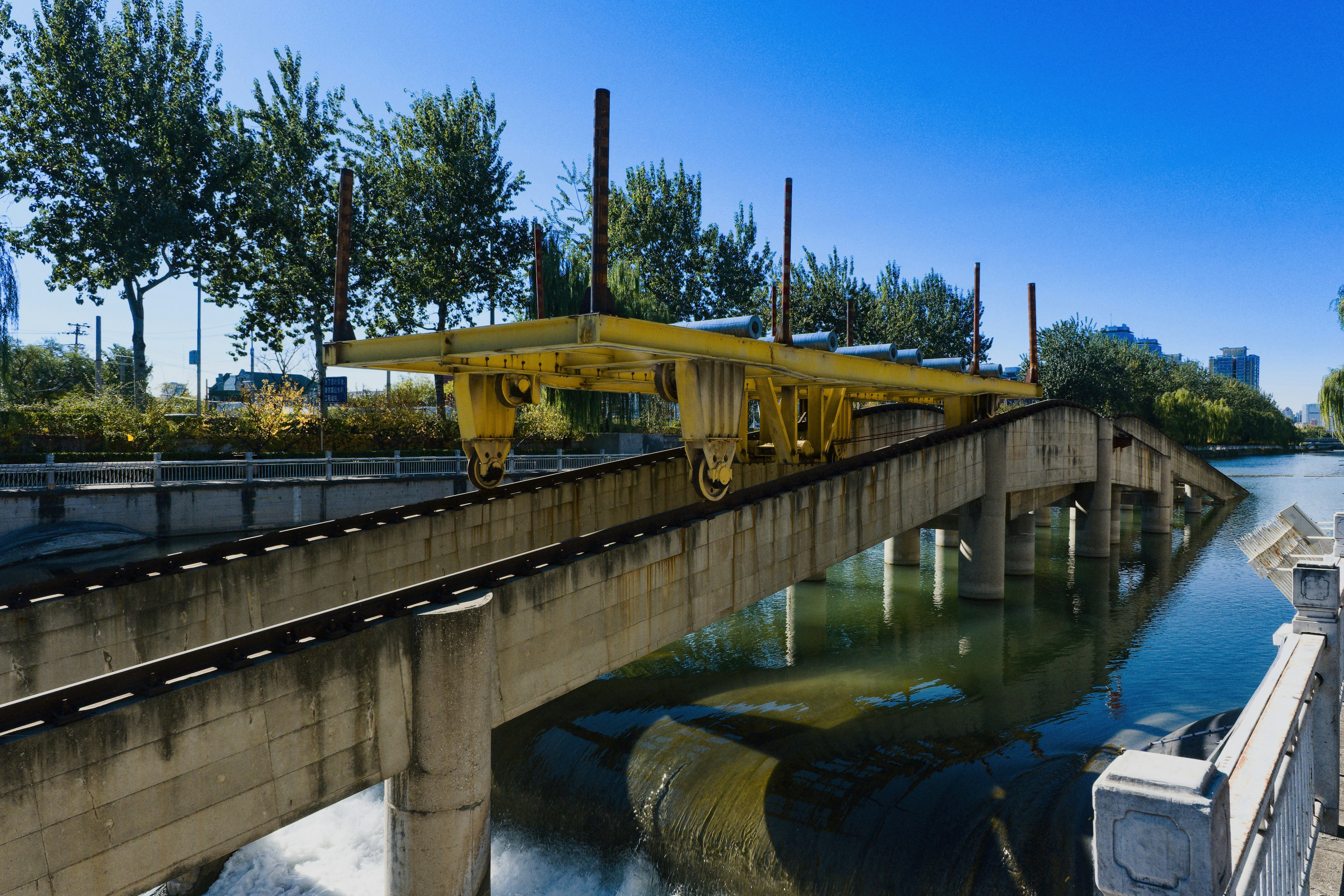 Yellow construction crane over a concrete bridge and water.