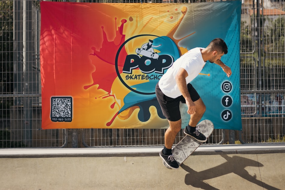 Skateboarder performing a trick in front of a colorful banner