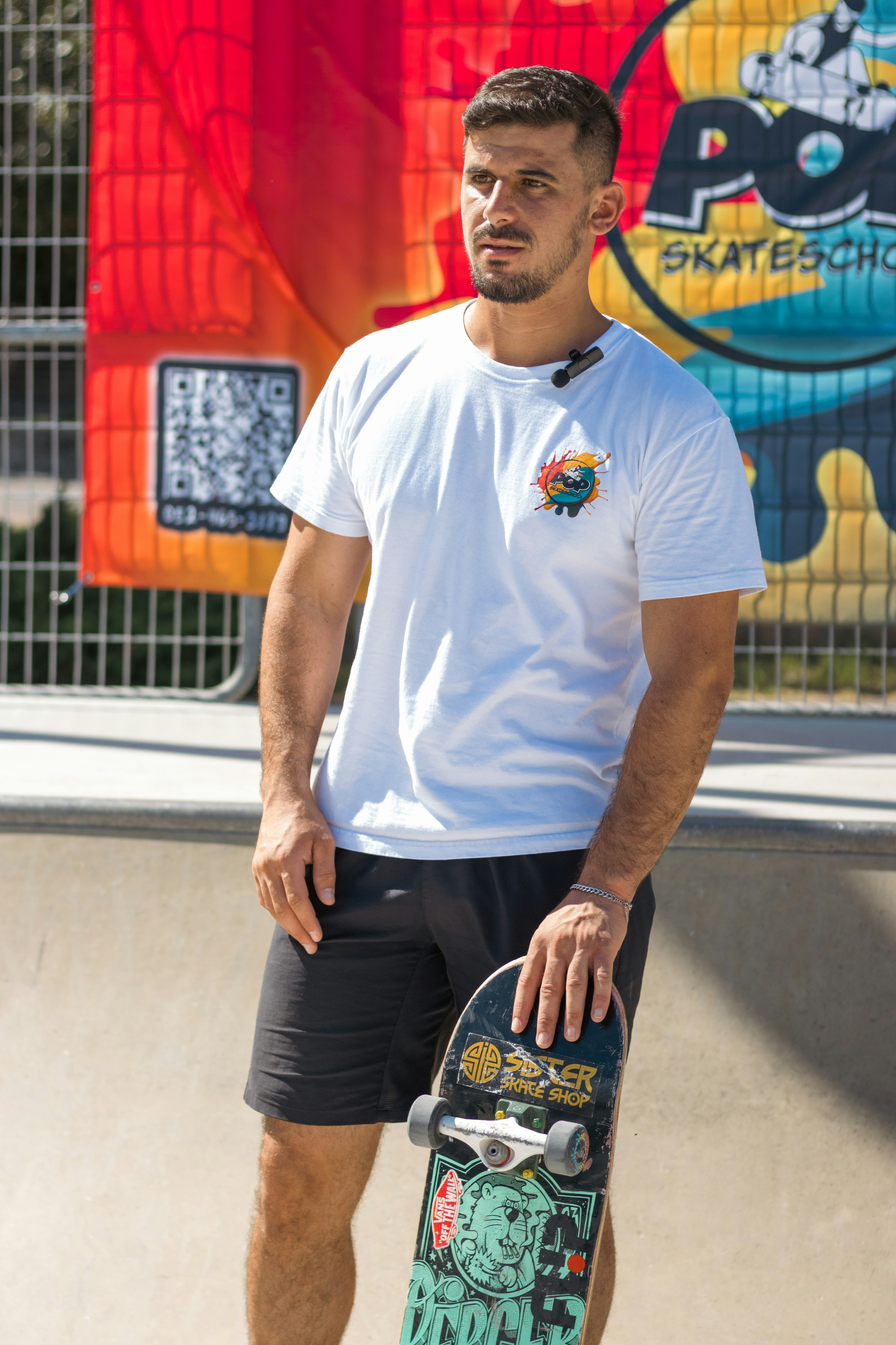 Man holding a skateboard in a skatepark.