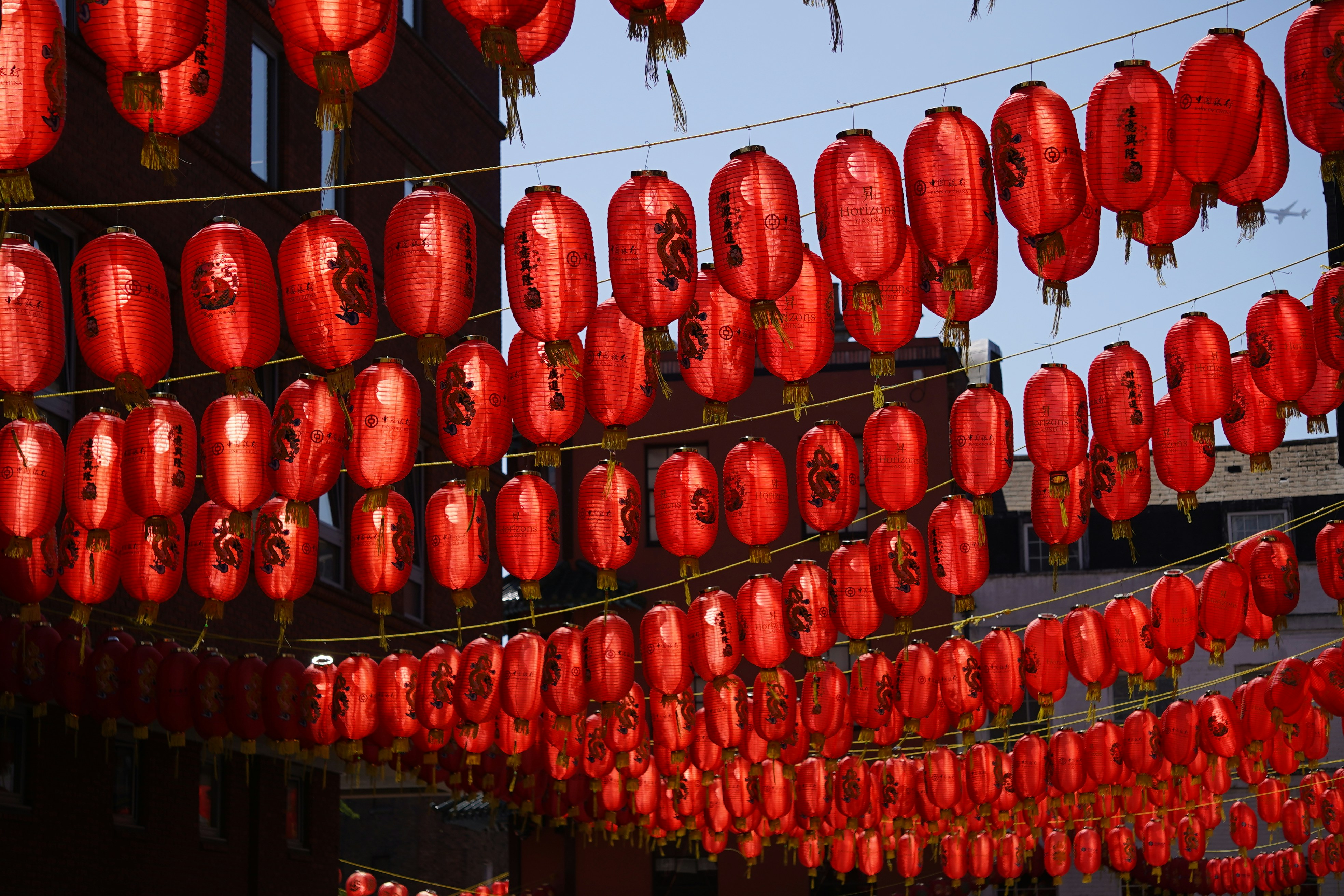 Rows of red lanterns hang against a blue sky.