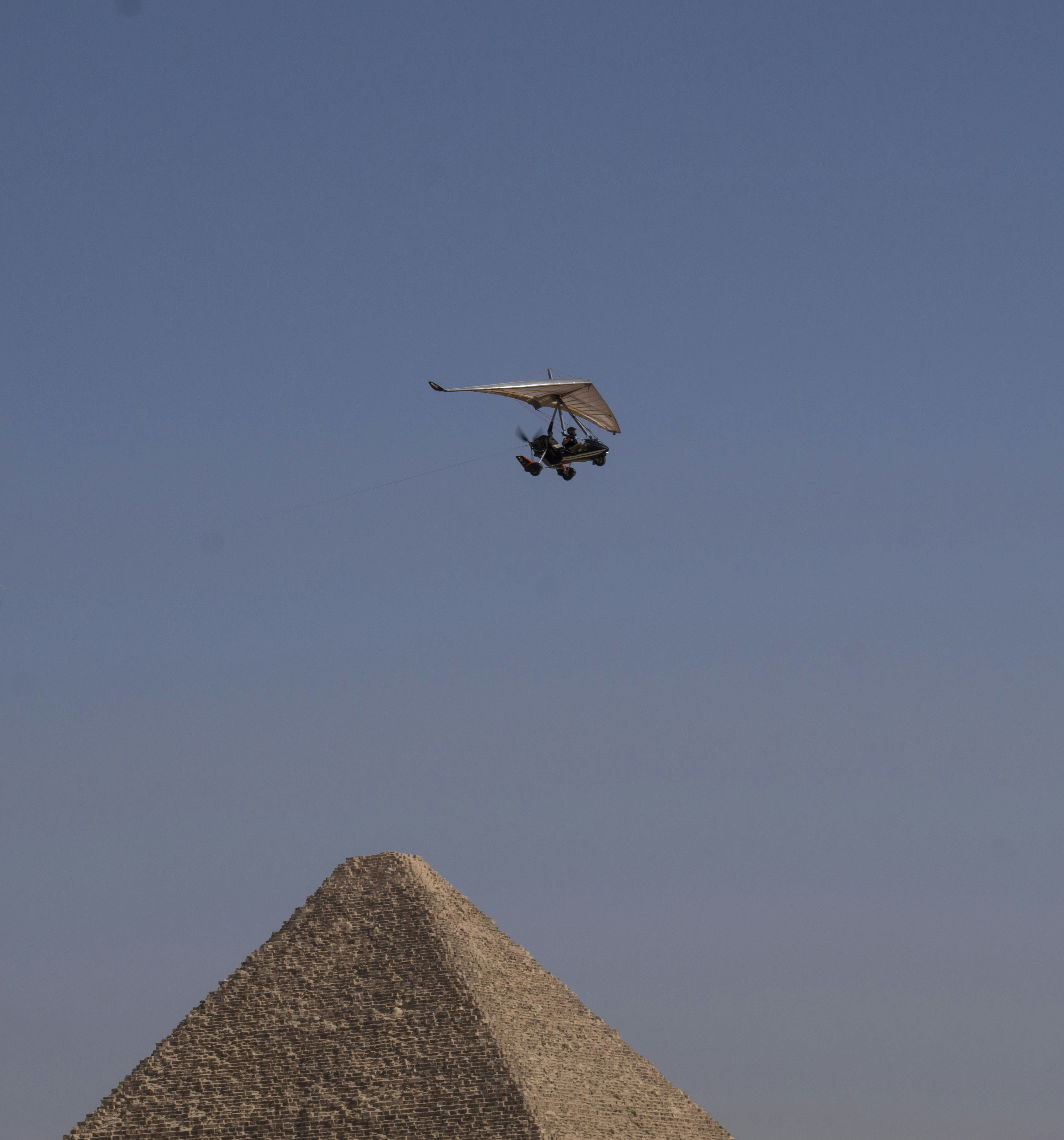 A hang glider flies over a pyramid