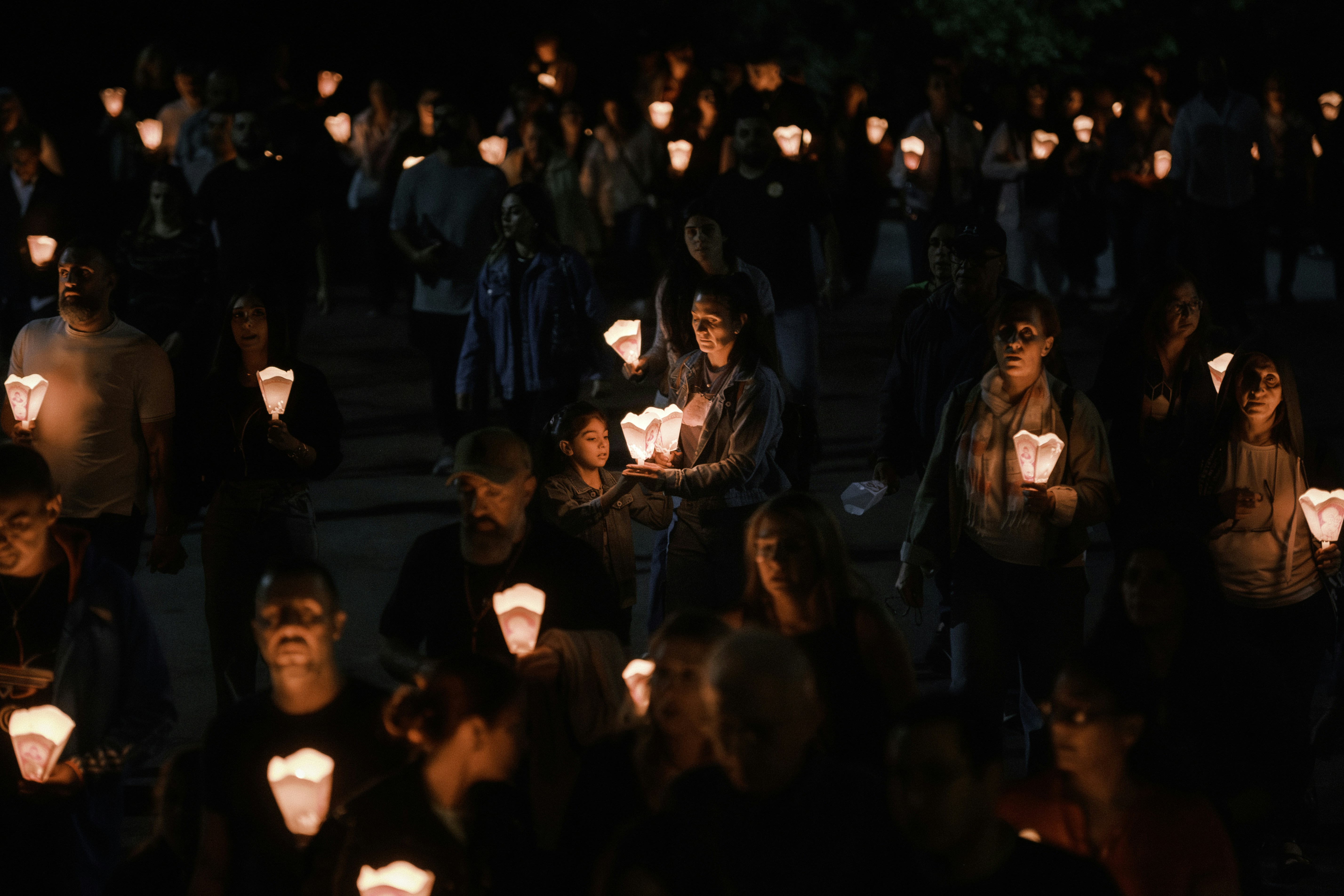 A crowd of people holding candles at night.