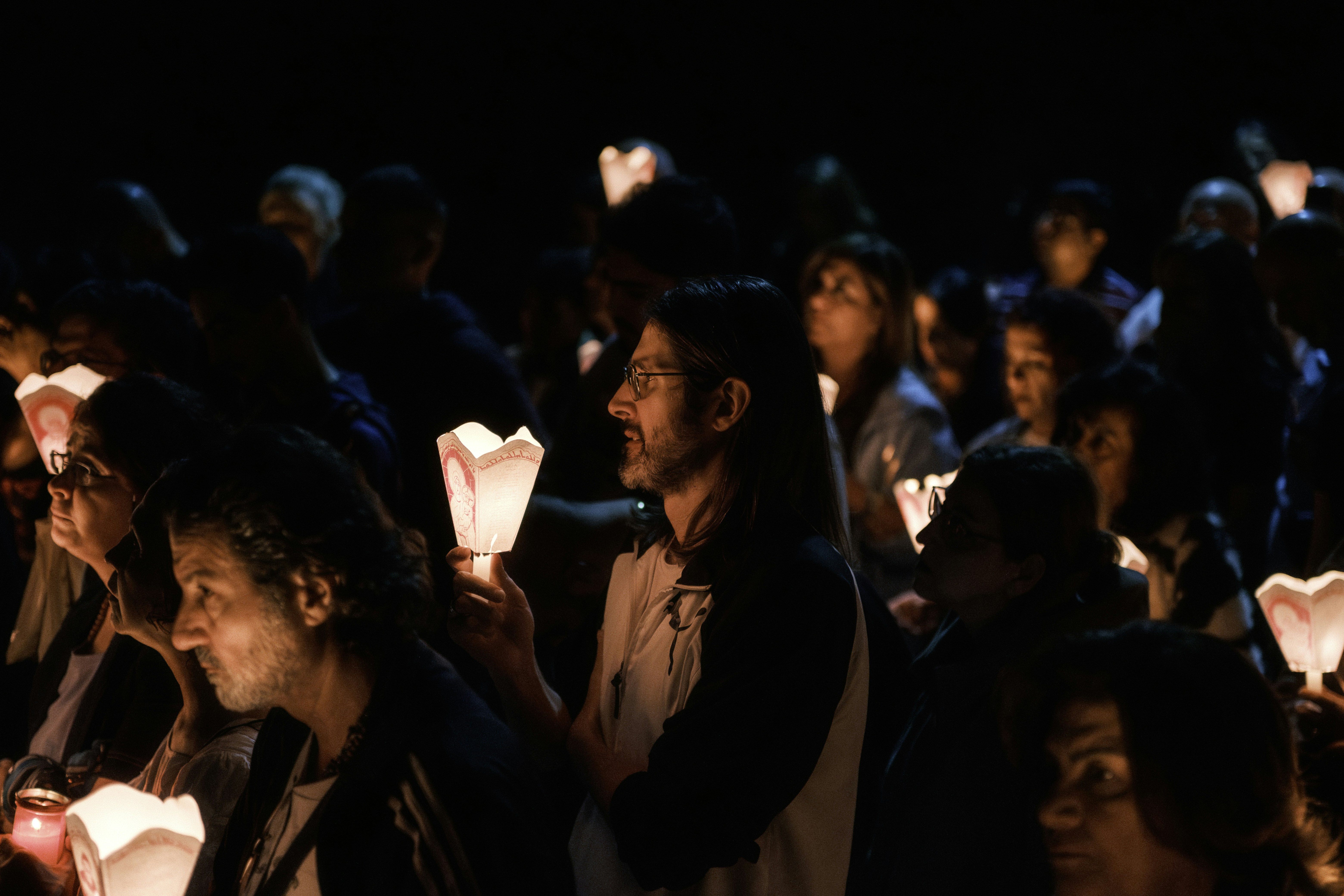 A crowd of people holding glowing candles at night