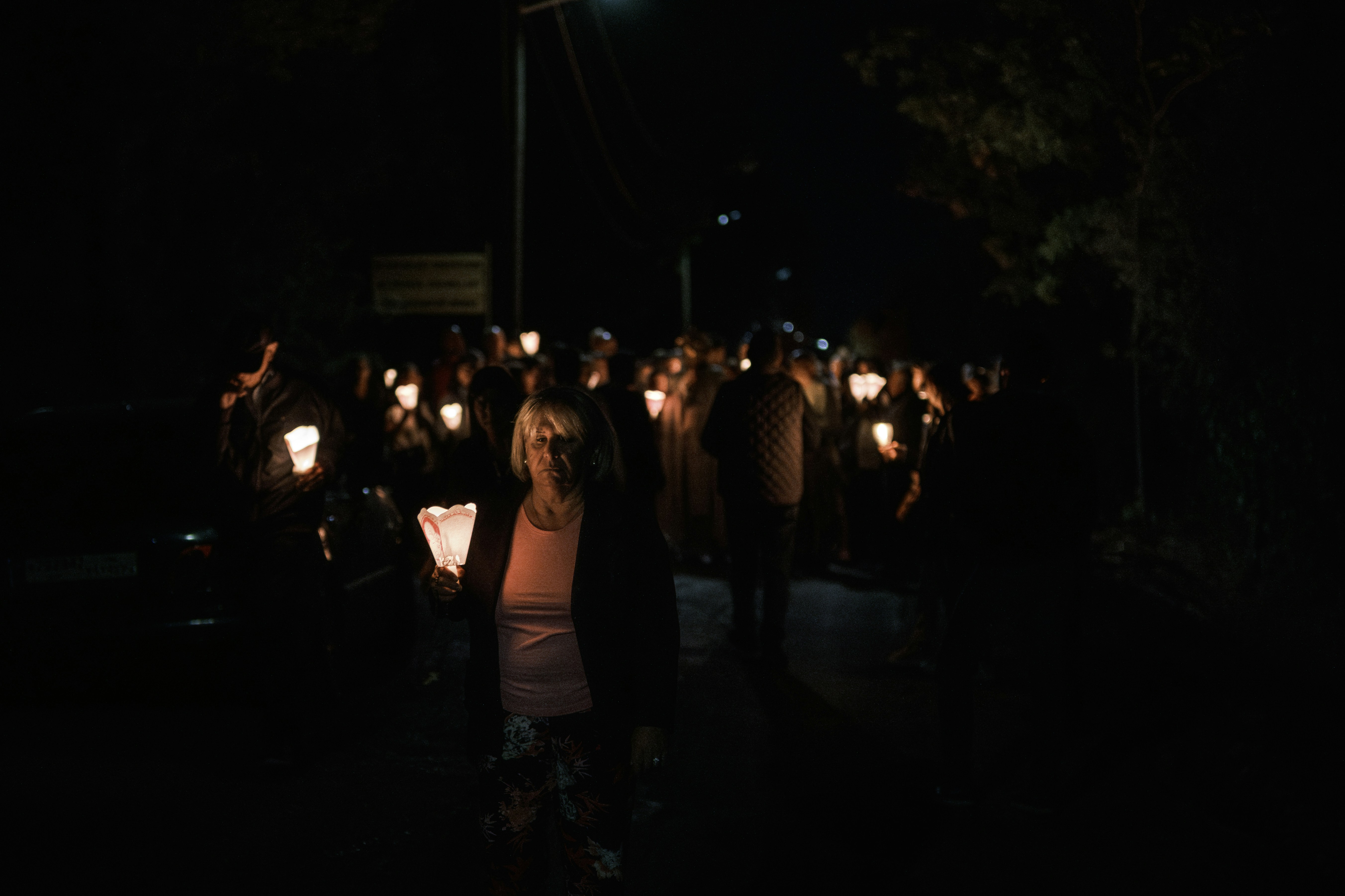 People holding candles walking at night