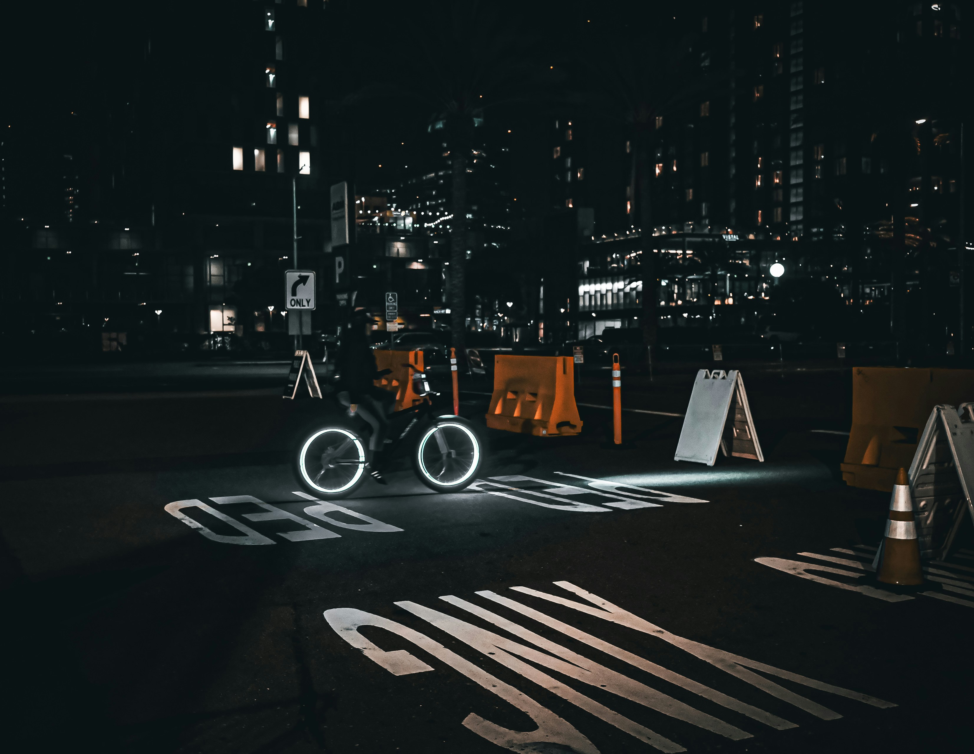 A cyclist rides through a city street at night.