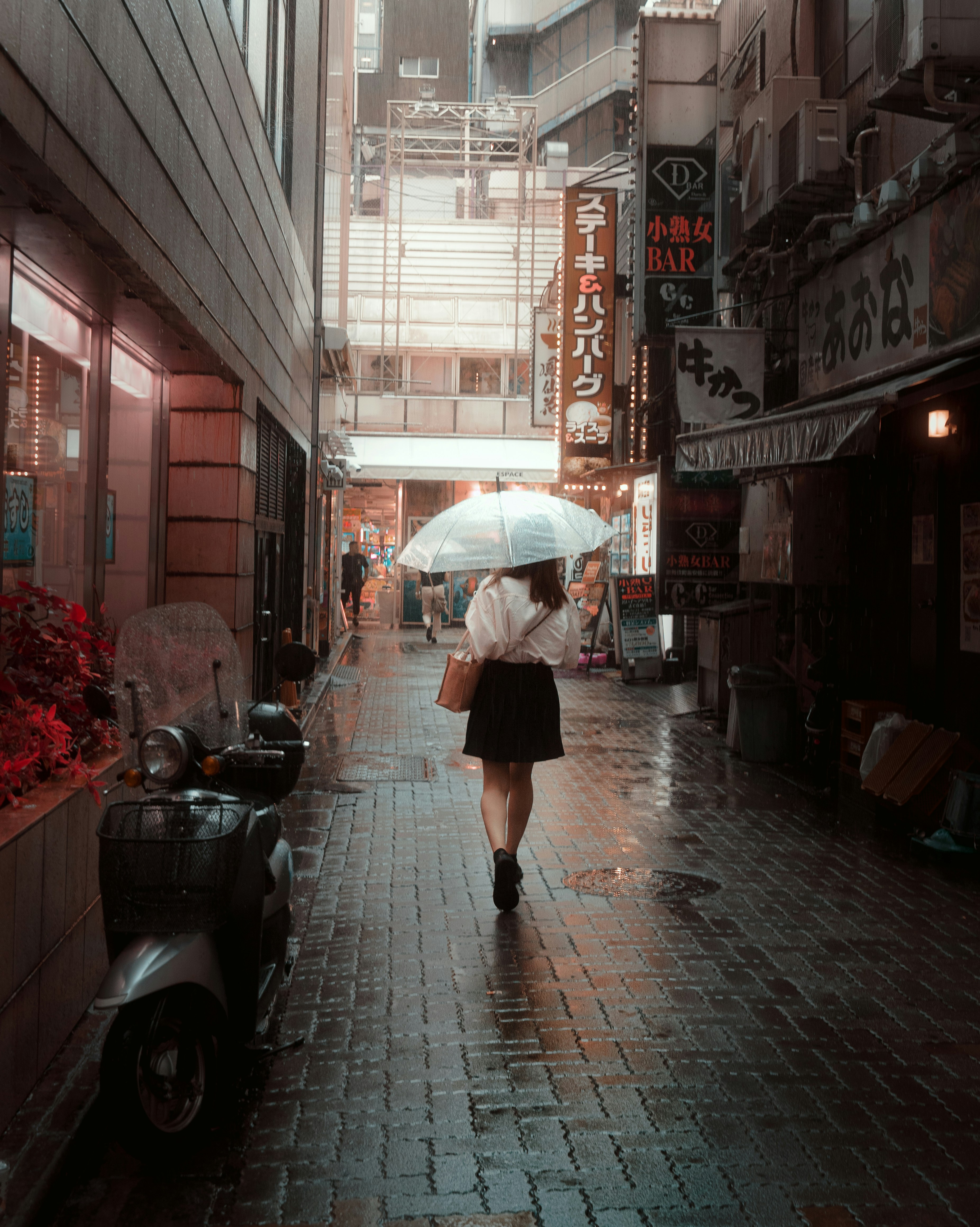Woman with umbrella walks down rainy city street.