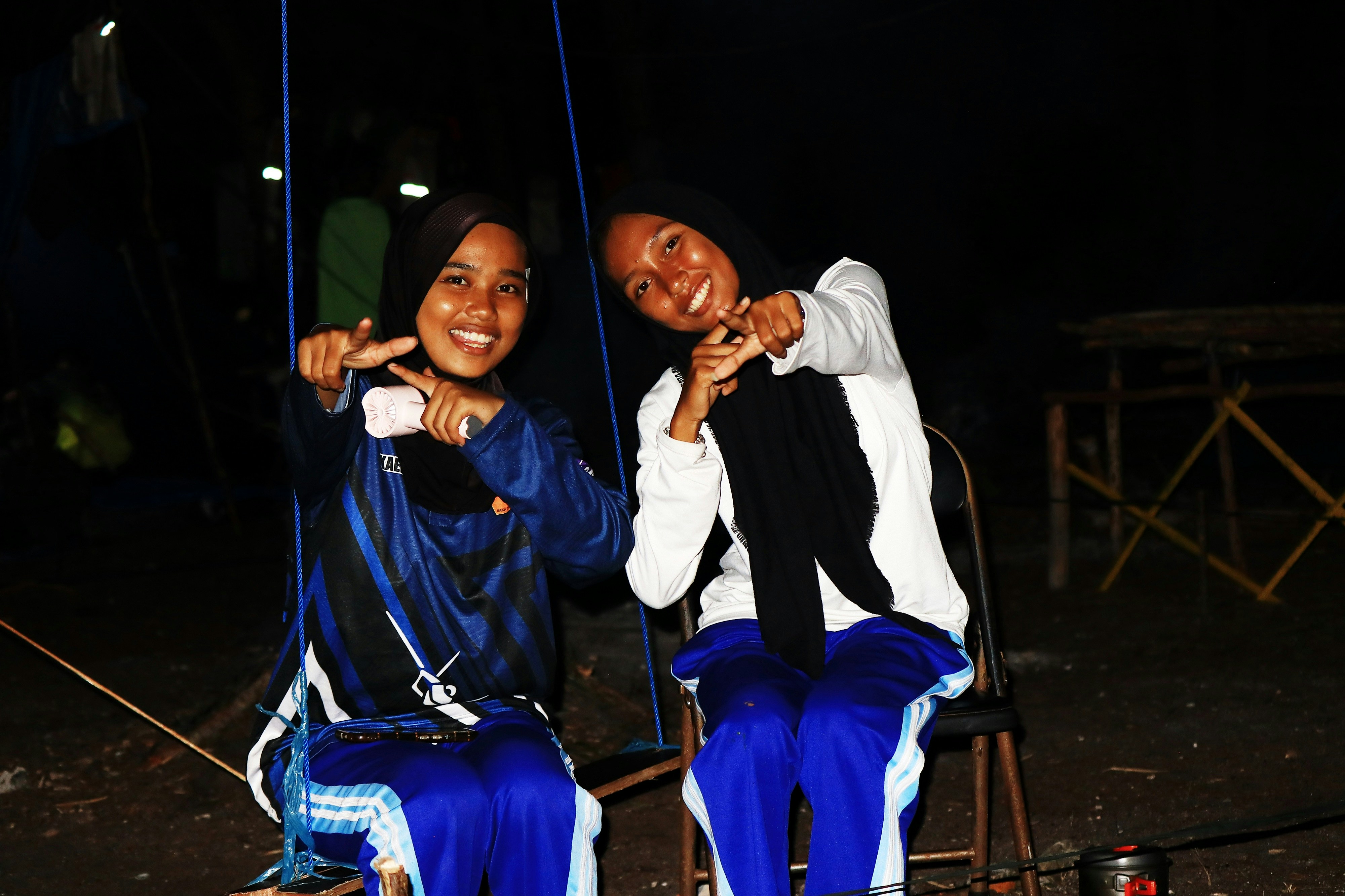 Two smiling young women posing for the camera at night.