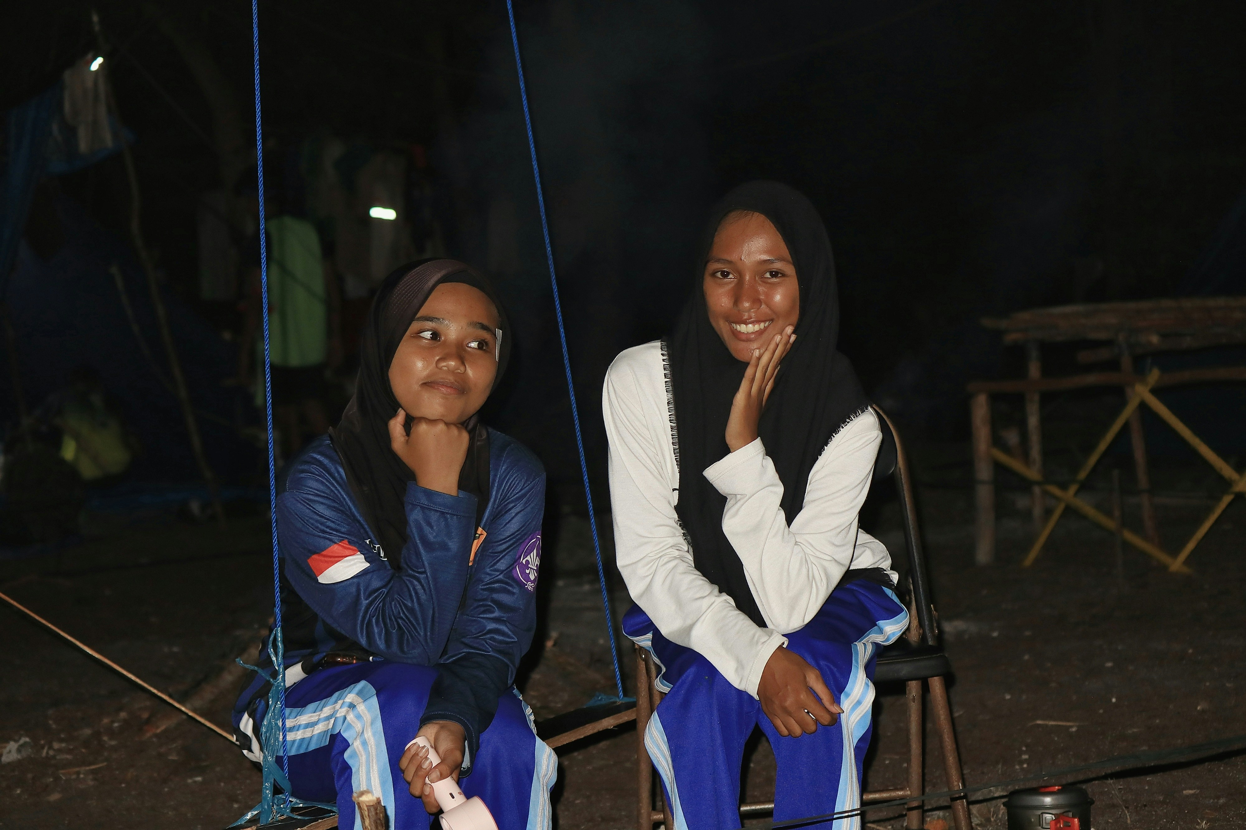 Two young women sitting outdoors at night
