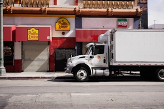 White truck parked on city street near businesses.