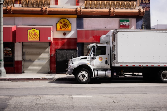 White truck parked on city street near businesses.