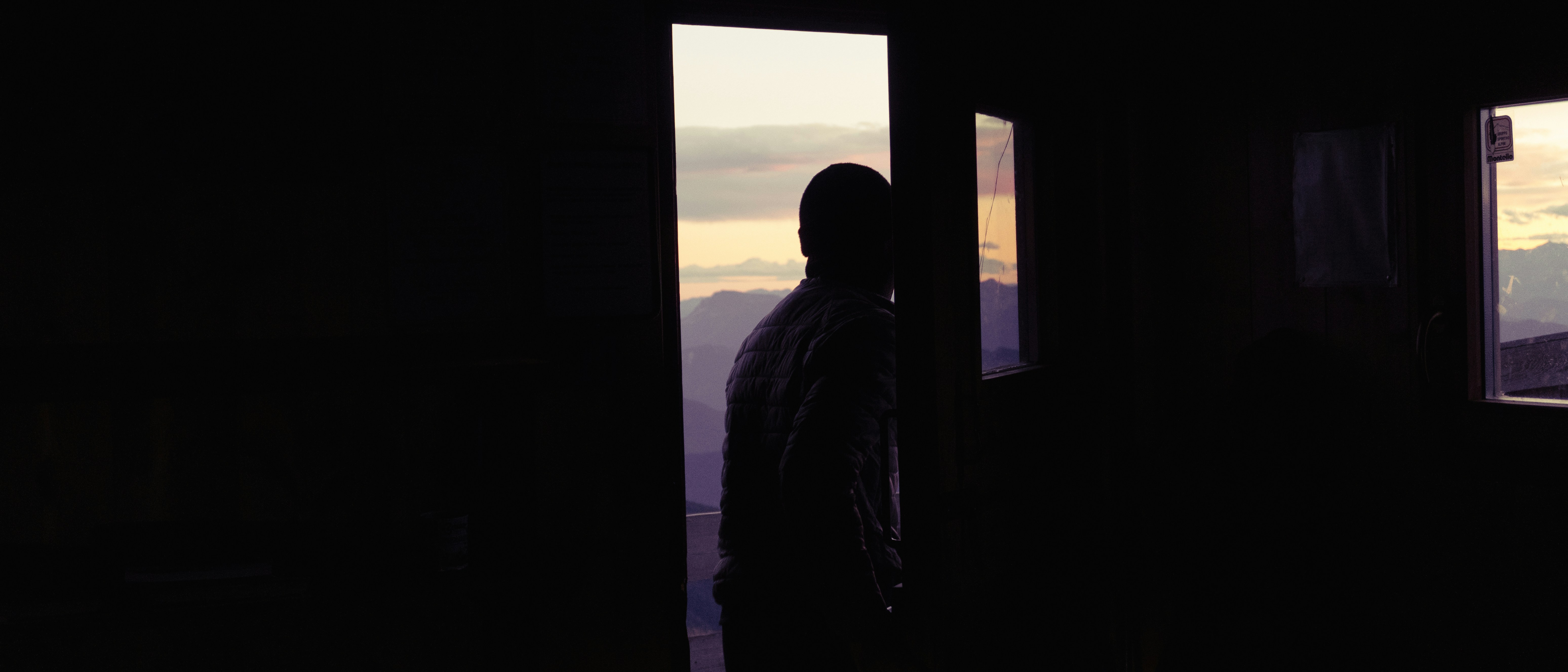 Man silhouetted in doorway looking at sunset