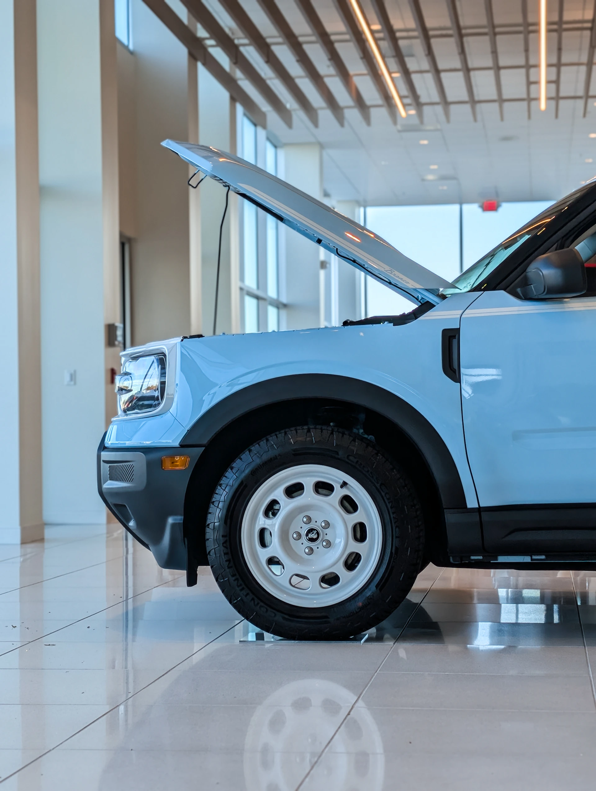Light blue suv with hood open indoors