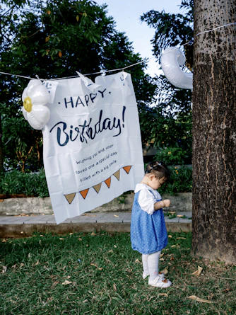 Girl in blue dress near birthday banner with balloons in mosquito-free yard treated by Evergreen