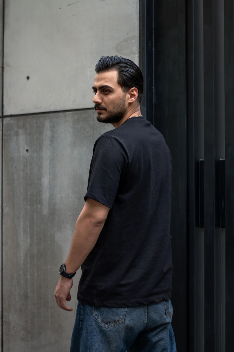 Man in a black t-shirt against a concrete wall