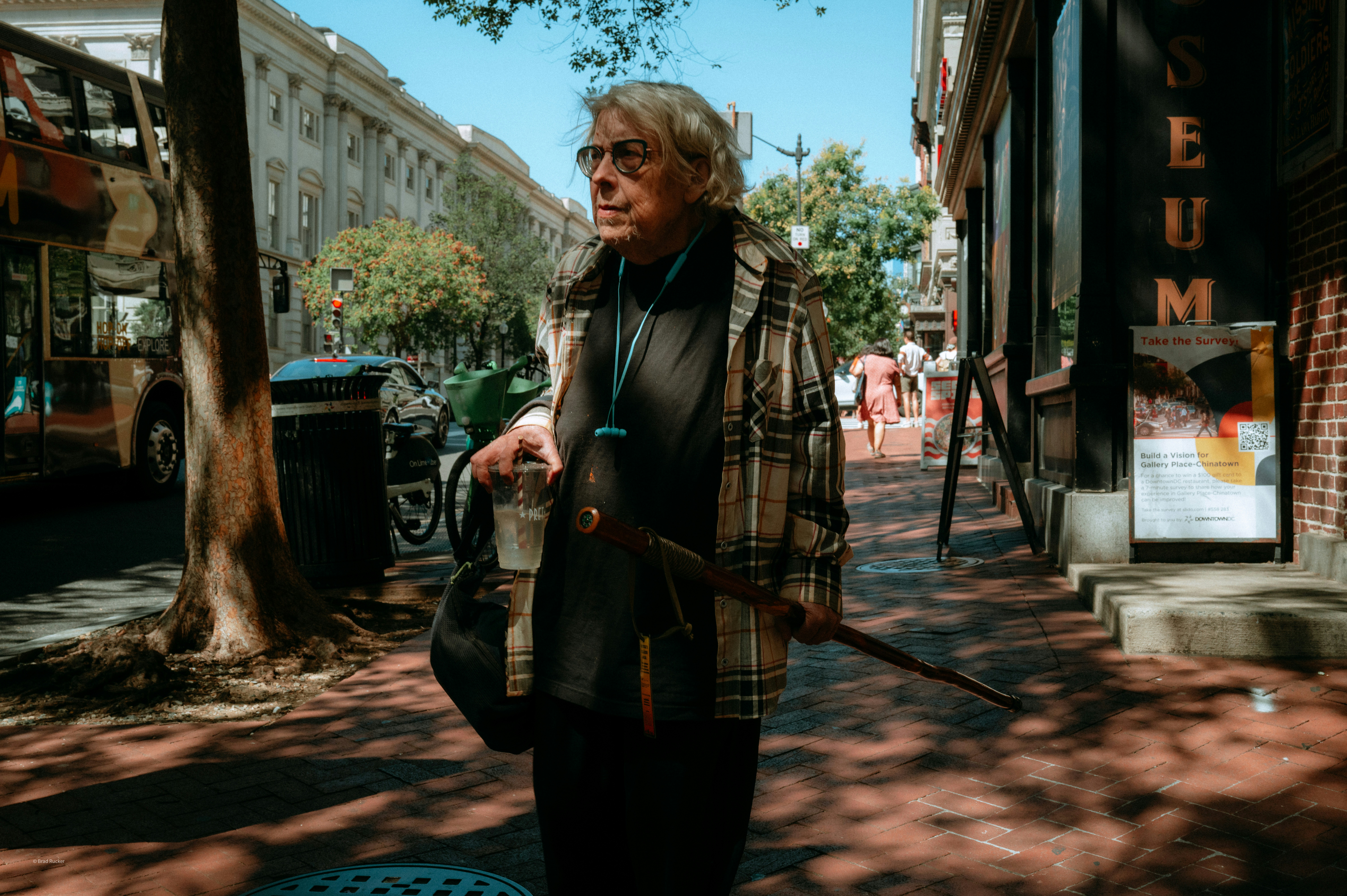 Elderly man walks down a sunny city street.
